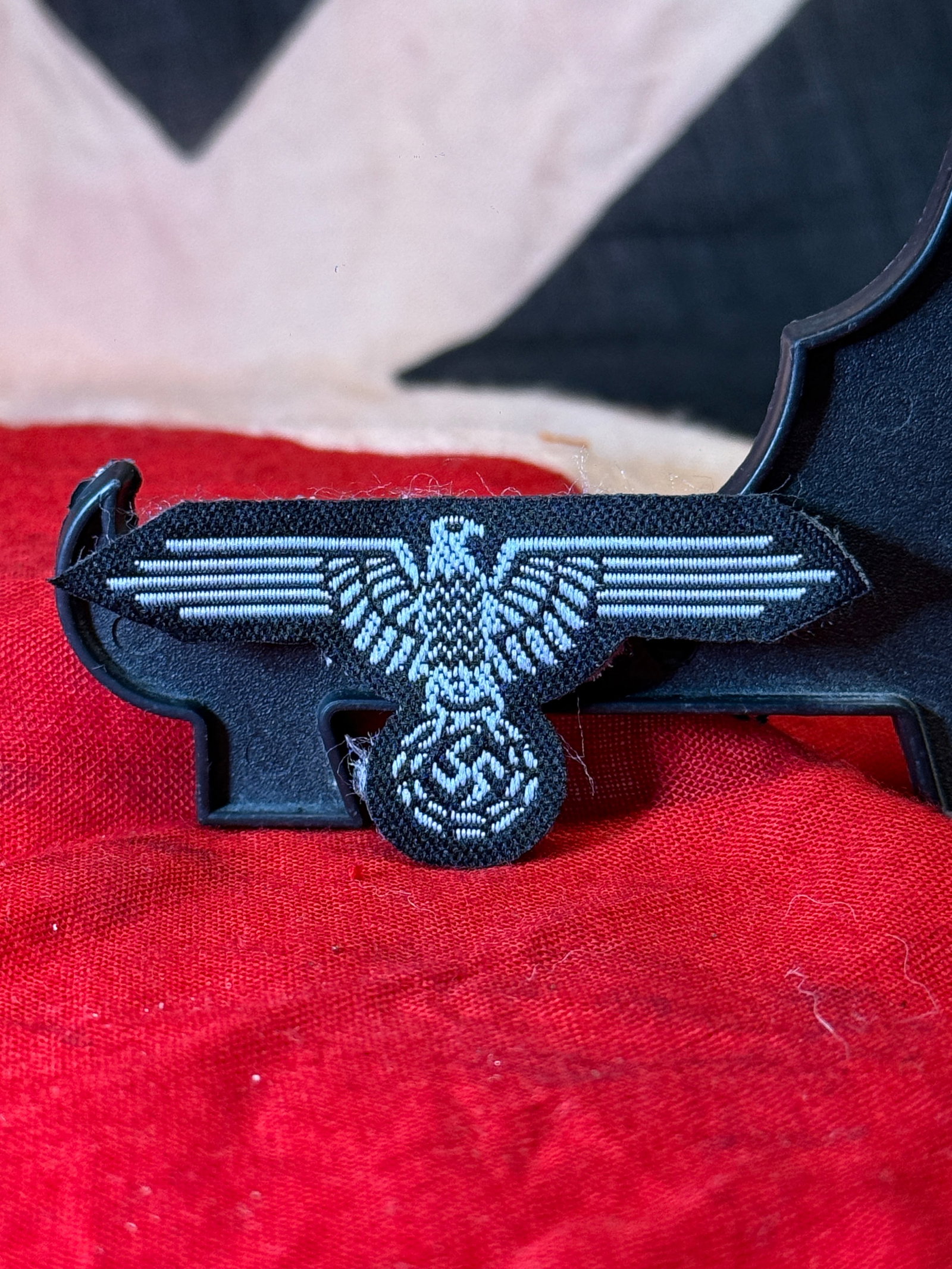 WWII German Waffen-SS Sleeve Eagle: This WWII German Waffen-SS sleeve eagle is embroidered in silver-gray thread on a black cloth backing and depicts the spread-wing eagle above a wreath enclosing a swastika. Worn on the upper sleeve of
