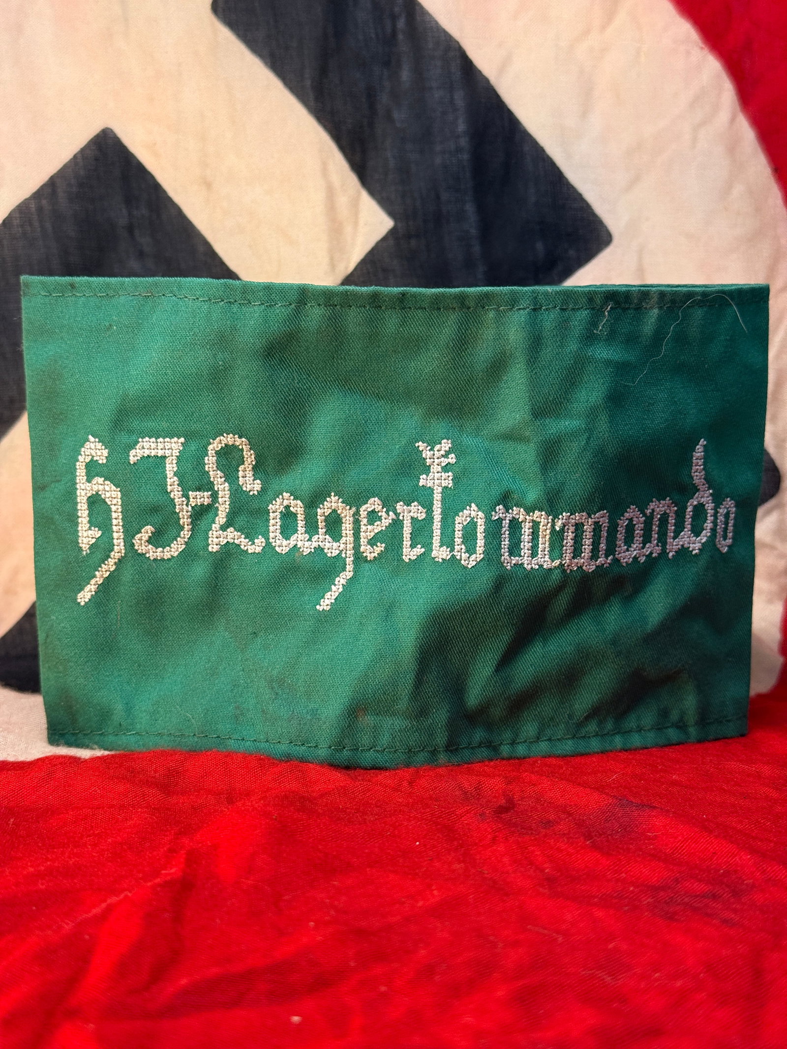WWII German Hitler Youth (HJ) Lagerkommando Armband With RZM Paper Tag: This WWII German Hitler Youth (HJ) Lagerkommando armband is constructed of green cloth with the word "HJ Lagerkommando" embroidered across the front in silver-gray thread. The reverse retains an origi
