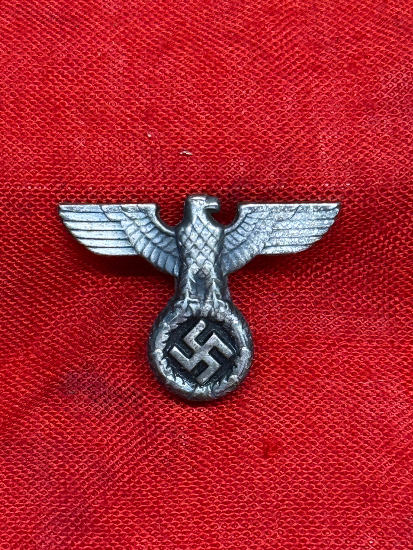 WWII German NSDAP Political Cap Eagle Badge: This WWII German NSDAP Political Cap Eagle badge depicts the national eagle with outstretched wings above a wreath enclosing a swastika, the standard insignia worn on National Socialist political viso