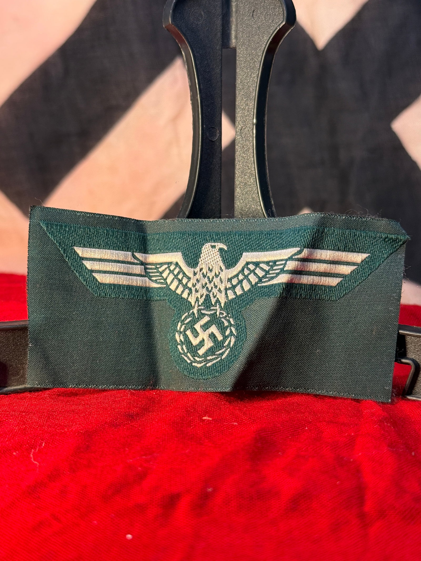 WWII German BeVo Woven Political Eagle Sleeve Insignia: This WWII German BeVo woven political eagle sleeve insignia features a finely woven national eagle with outstretched wings clutching a wreath enclosing a swastika on a dark green cloth backing. Produc