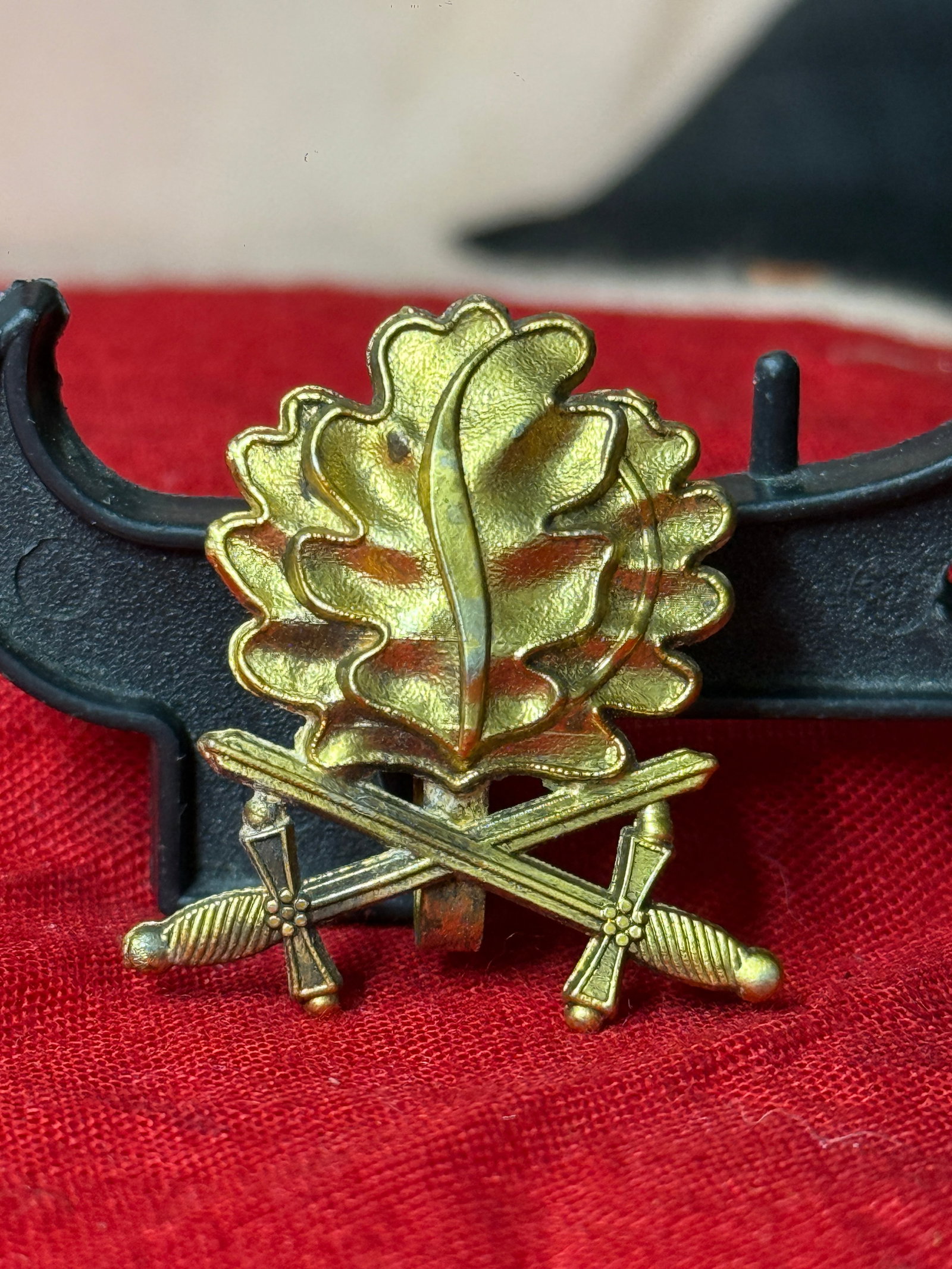 WW2 German Gold-Tone Oak Leaf & Crossed Swords Military Collar Insignia Pin Marked 900 L/50: Gold-tone metal military-style insignia featuring a detailed oak leaf above a pair of crossed swords. The reverse has a vertical attachment clip and is clearly marked “900” and “L/50.”