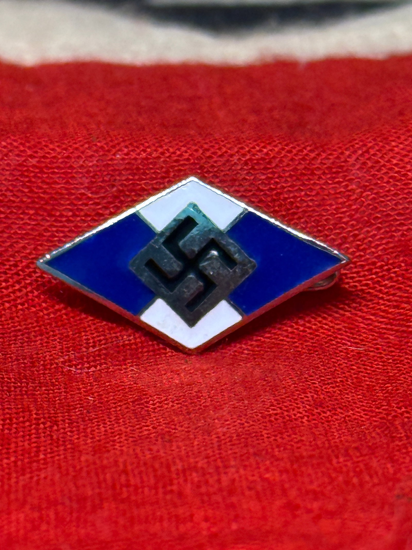 WWII German Hitler Youth (HJ) Membership Diamond Badge By Otto Hoffmann Ges. Gesch.: The Hitler Youth Membership Diamond features the familiar blue-and-white enamel diamond with a central black swastika, worn by members of the Hitlerjugend (HJ) during the Second World War. The reverse
