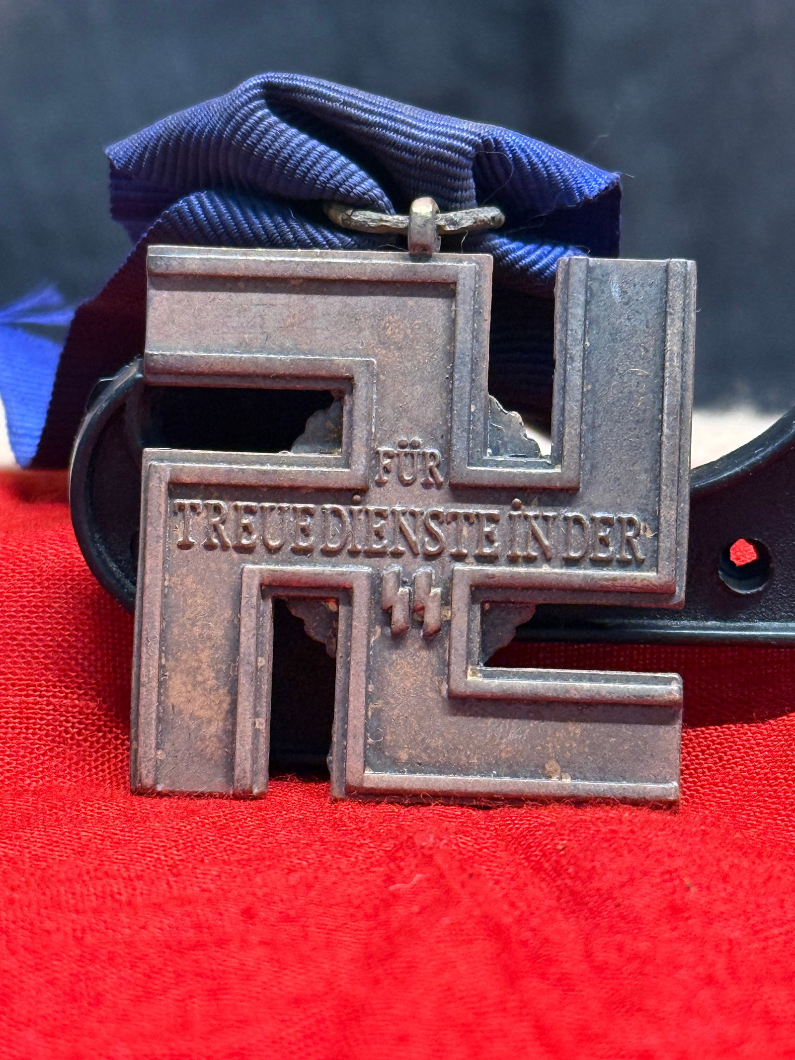 WWII German SS 12-Year Long Service Medal With Blue Ribbon: This WWII German SS 12-Year Long Service Medal features the distinctive stepped cross design with the inscription "Für Treuedienste in der SS" ("For Faithful Service in the SS") across the obverse, w