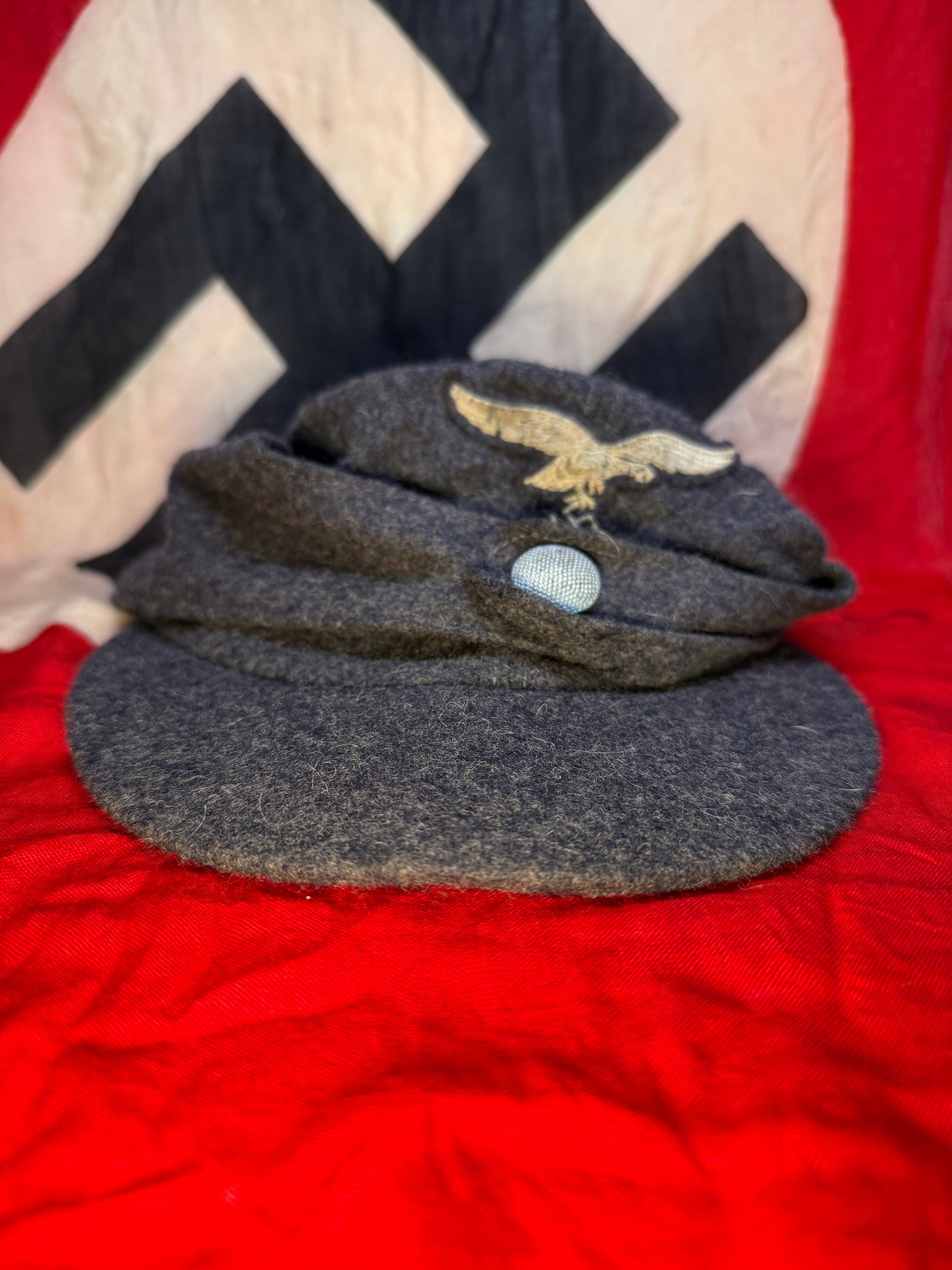 WWII German Luftwaffe M43 Field Cap: This blue-gray wool Luftwaffe M43 field cap features the embroidered Luftwaffe eagle insignia on the front fold, pebbled aluminum front buttons, and a cloth-lined interior with stamped size marking "5