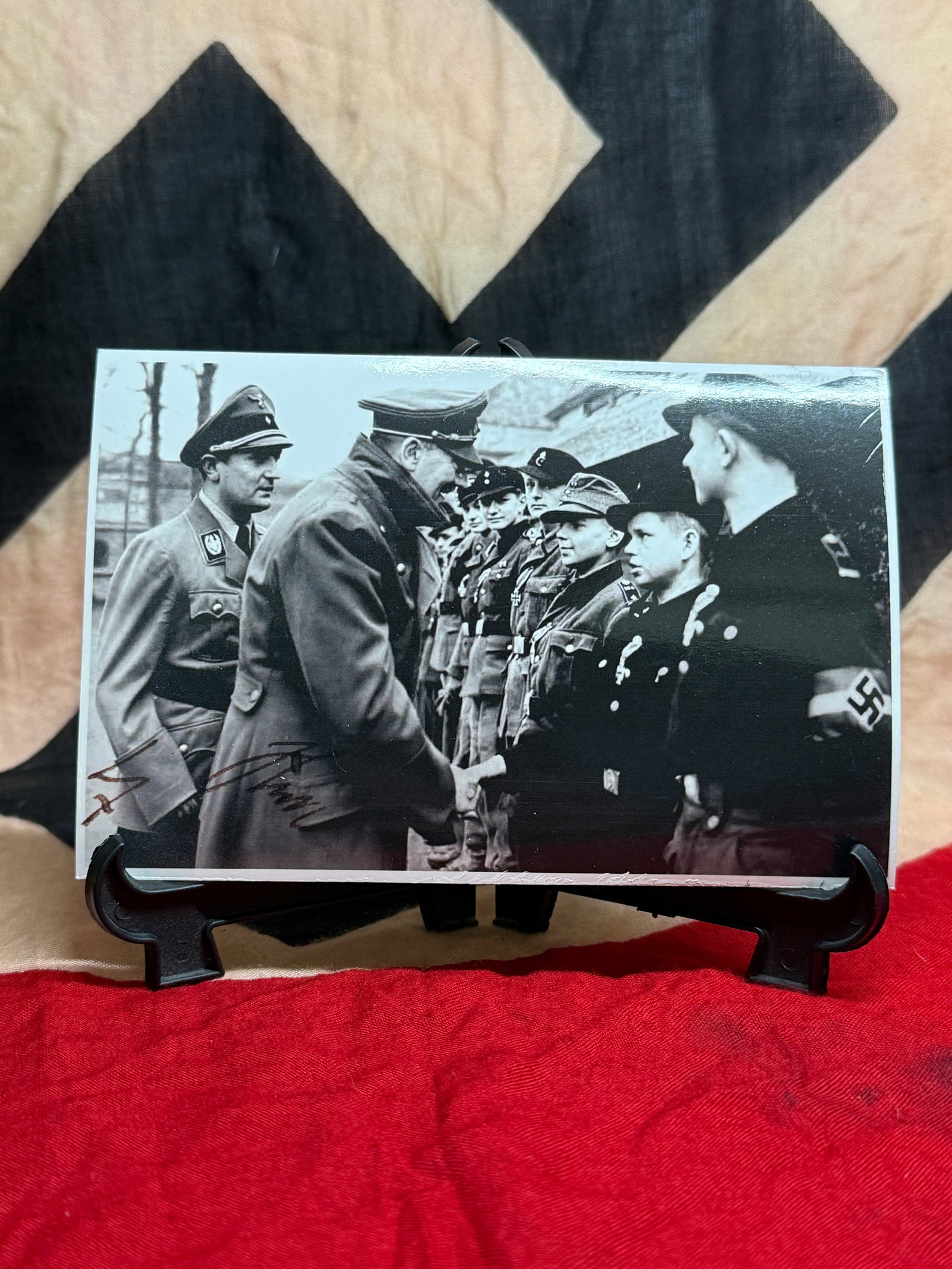 WWII German Adolf Hitler Signed Photograph: This black-and-white photograph depicts Adolf Hitler greeting members of the Hitler Youth while accompanied by senior officials, with a signature appearing along the lower front margin. Images of this
