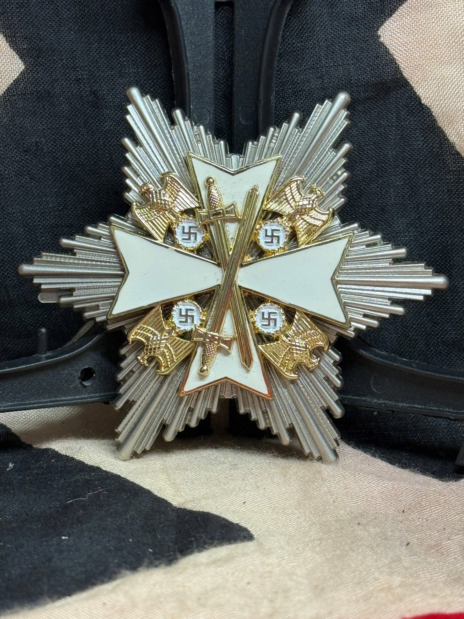 WWII German War Merit Cross Grand Cross Breast Star with Swords: This impressive multi-rayed breast star features the white enameled War Merit Cross with crossed swords, gilt national eagles, and swastikas mounted upon a silver radiating starburst. The reverse reta