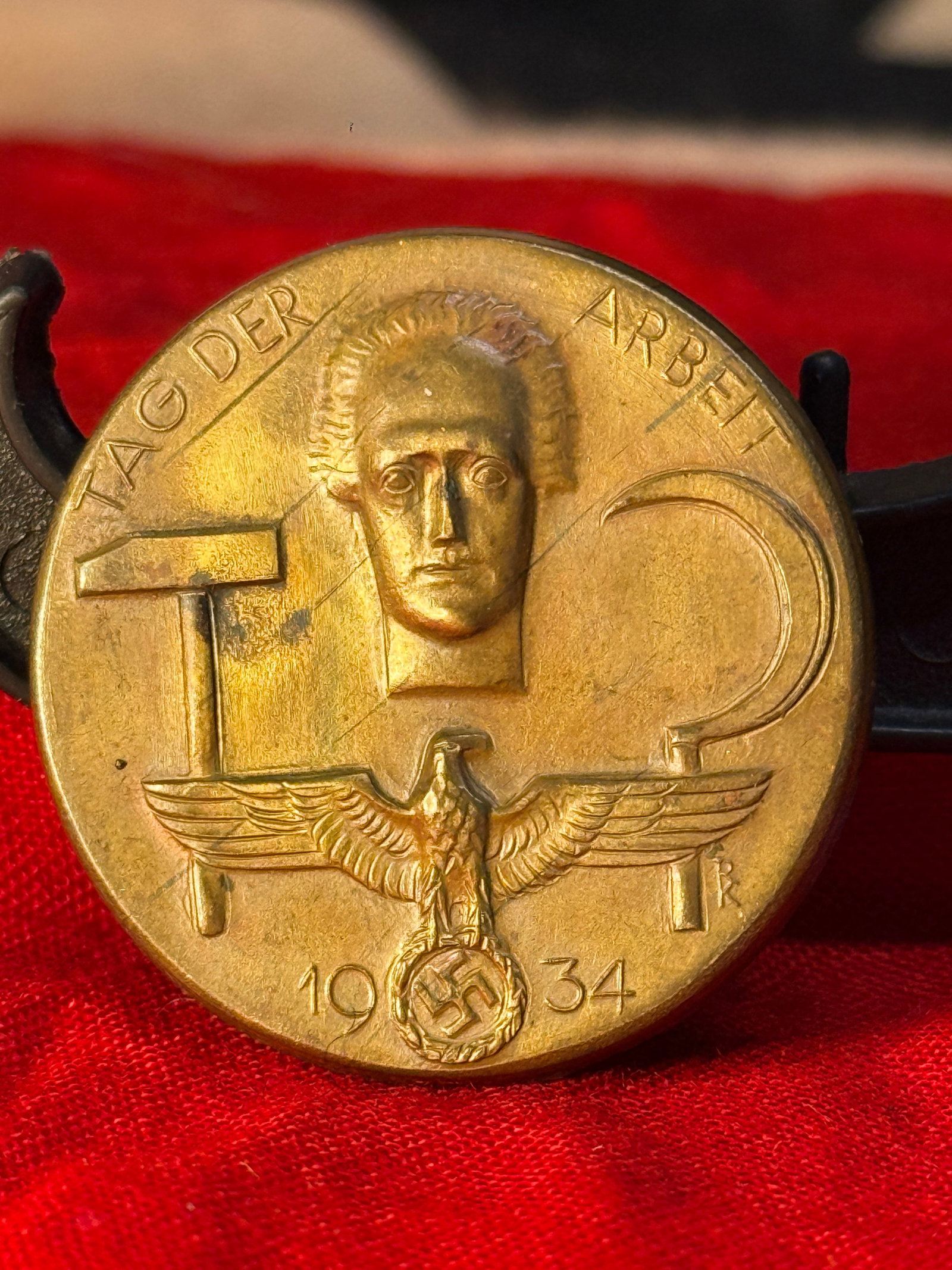 1934 German Tag der Arbeit Labor Day Commemorative Badge: This bronze-toned commemorative badge is dated 1934 and bears the inscription "Tag der Arbeit," featuring labor tools, a stylized portrait, and a German national eagle. The reverse retains its origina