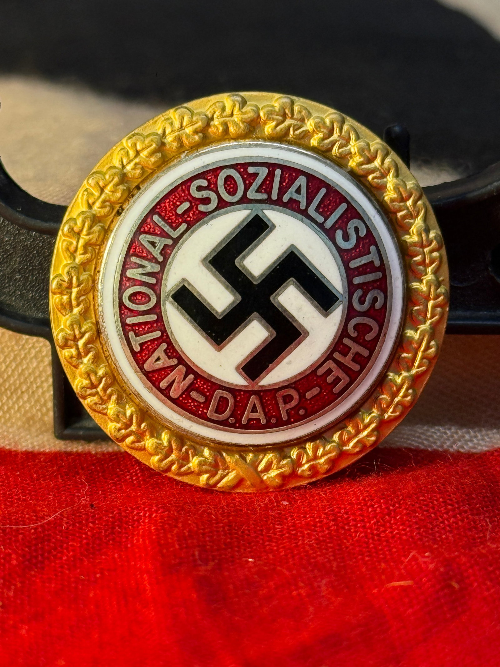WWII German NSDAP Social Welfare Membership Badge By Ges. Gesch. Deschler & Sohn Munchen 9 Serial No: This colorful enamel badge features the inscription "National-Sozialistische D.A.P." encircling a black swastika on a white field, bordered by a gold oak leaf wreath. The reverse is maker marked Desch