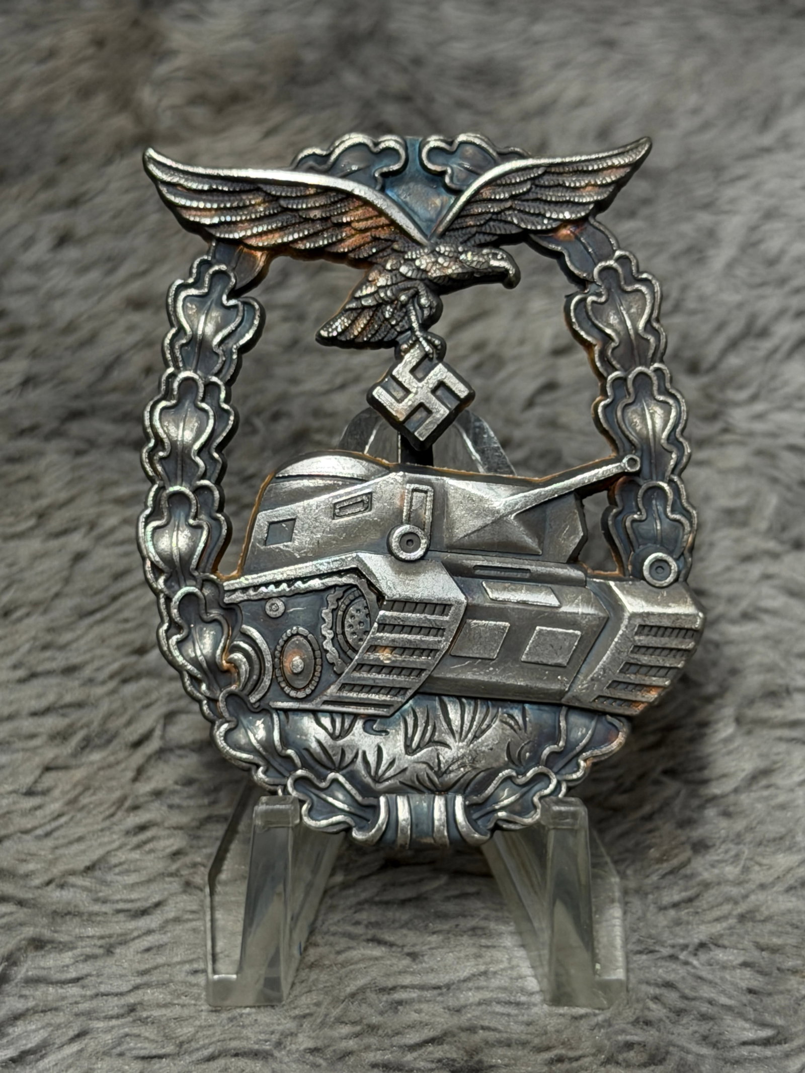 WWII German Heer Panzer Tank Assault Badge with Eagle & Oak Leaf Wreath: A dramatic WWII German Heer Panzer tank assault badge featuring a highly detailed armored fighting vehicle advancing across the center of an oval oak-leaf wreath. The upper portion is surmounted by a 