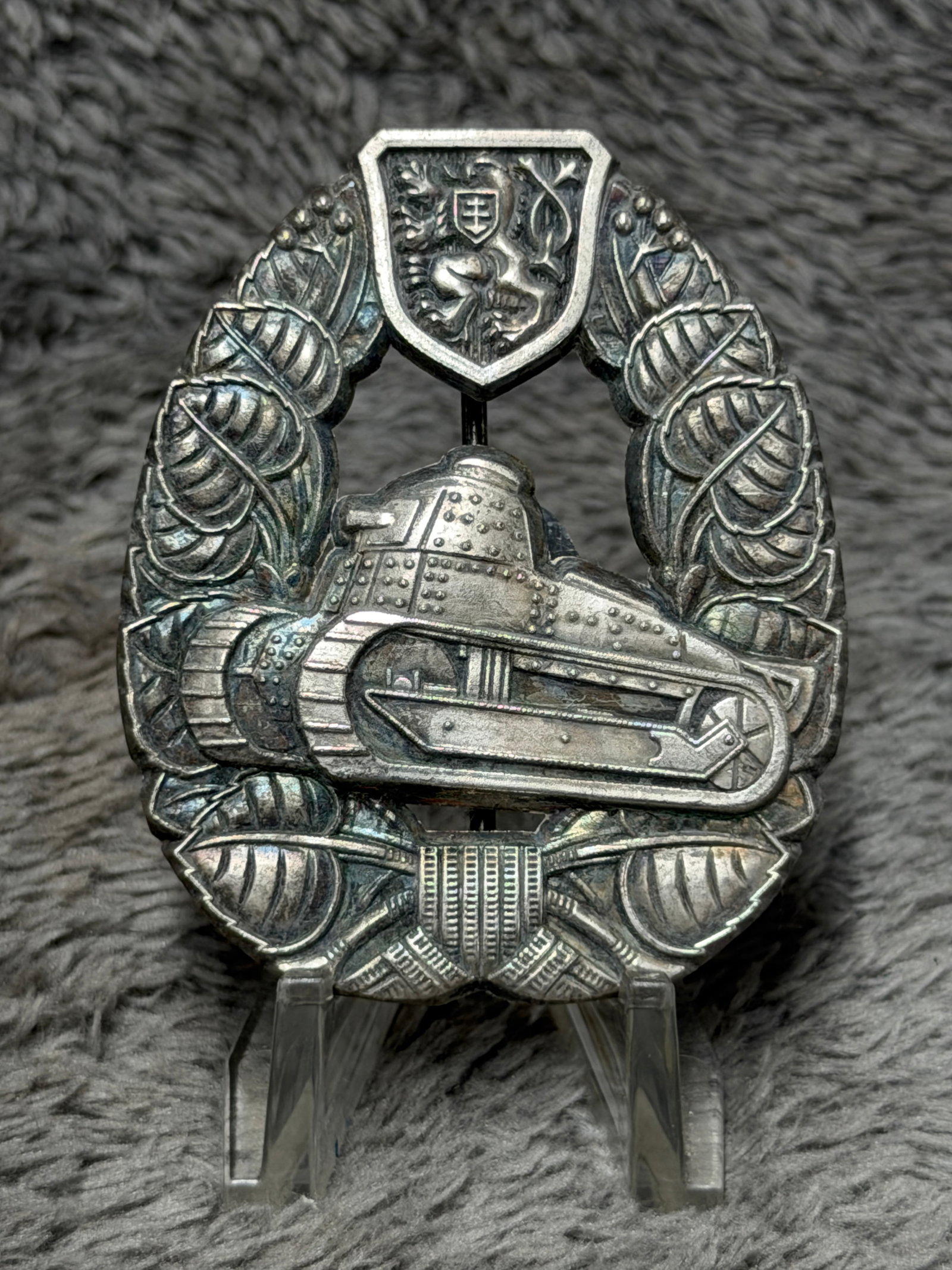WWII Slovak Armored Forces Tank Crew Qualification Badge: A striking WWII-era Slovak armored forces badge featuring a highly detailed riveted tank in raised relief at the center, surrounded by an elaborate wreath of stylized linden leaves, a traditional Slov