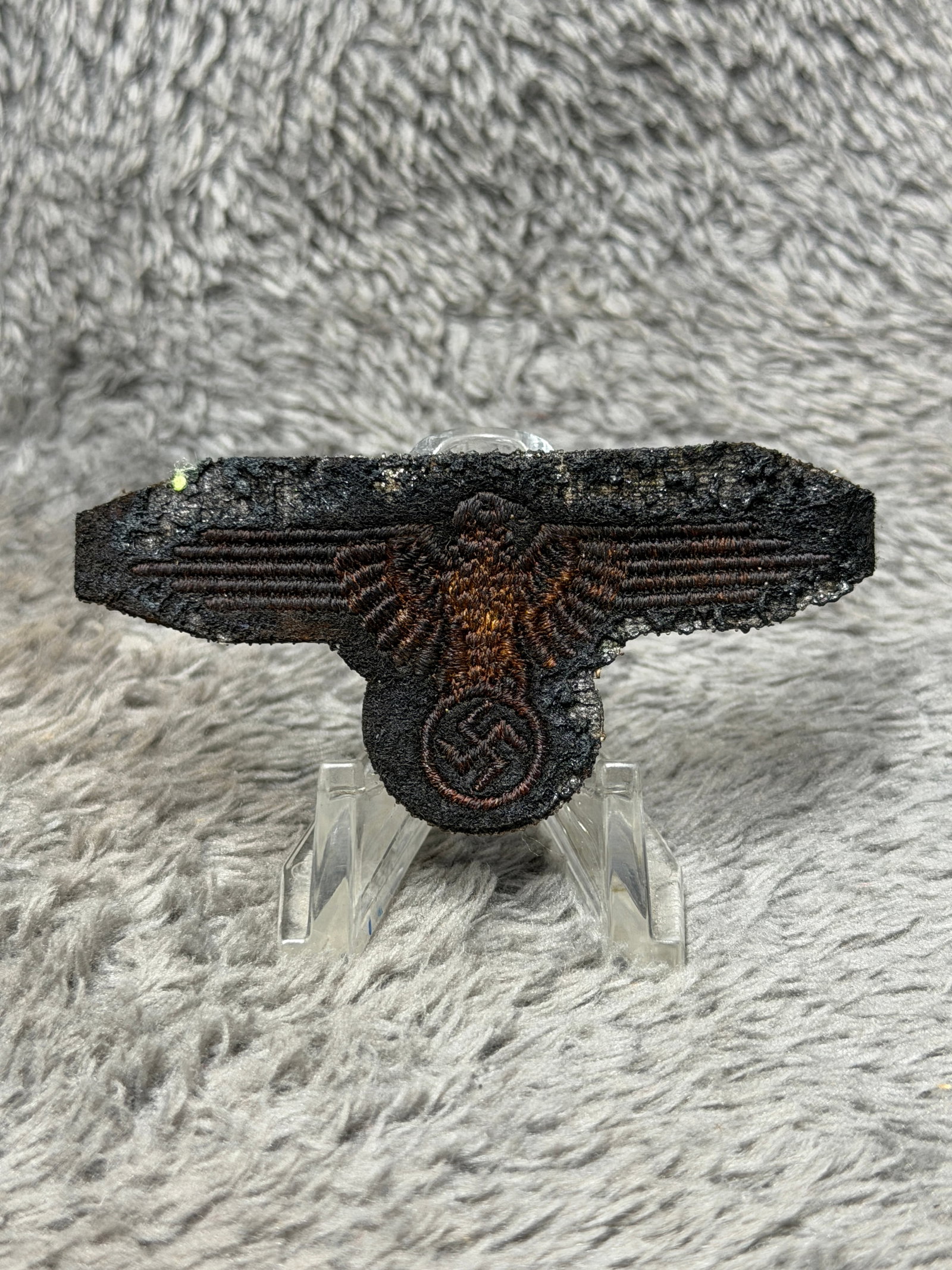 WWII German Waffen-SS Embroidered Breast Eagle Insignia – Dark Cloth: WWII German Waffen-SS embroidered breast eagle insignia featuring the characteristic spread-wing eagle positioned above and clutching a circular wreathed swastika. The insignia is executed in dark bro