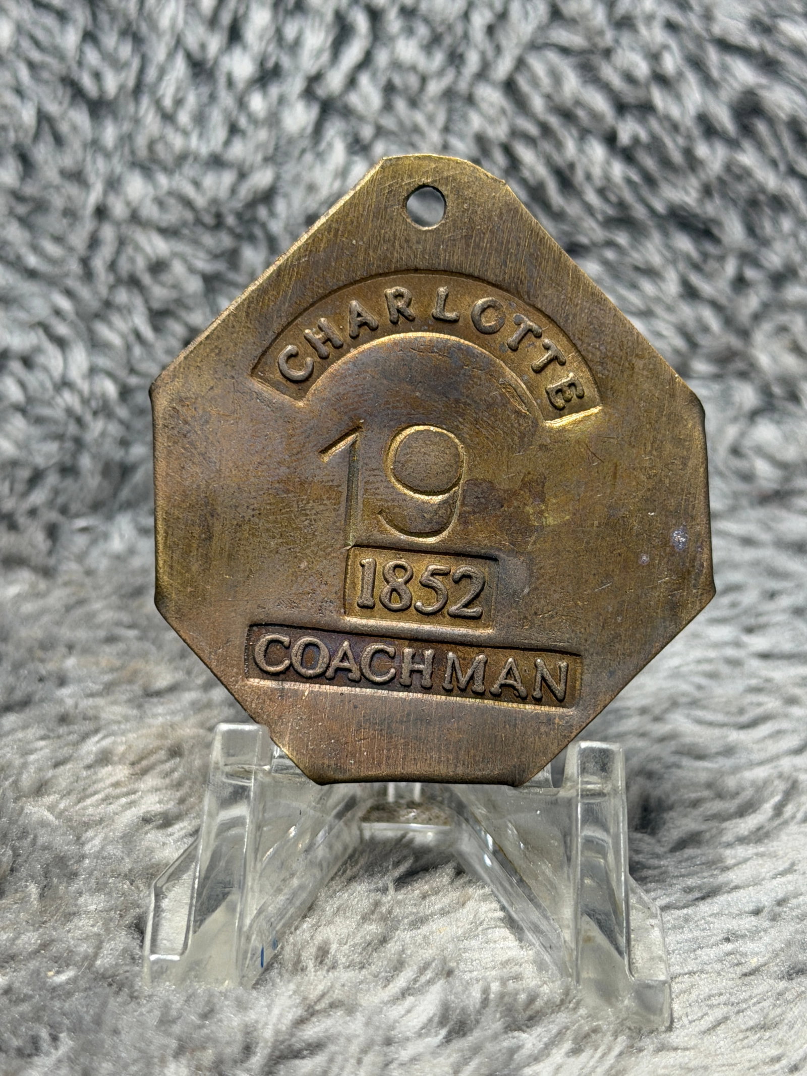 1852 Charleston, South Carolina Slave Hire Tag – Coachman No. 19: Mid-19th century Charleston, South Carolina slave hire tag dated 1852 and bearing the occupational designation “COACHMAN.” This substantial brass tag features a distinctive multi-sided form wi