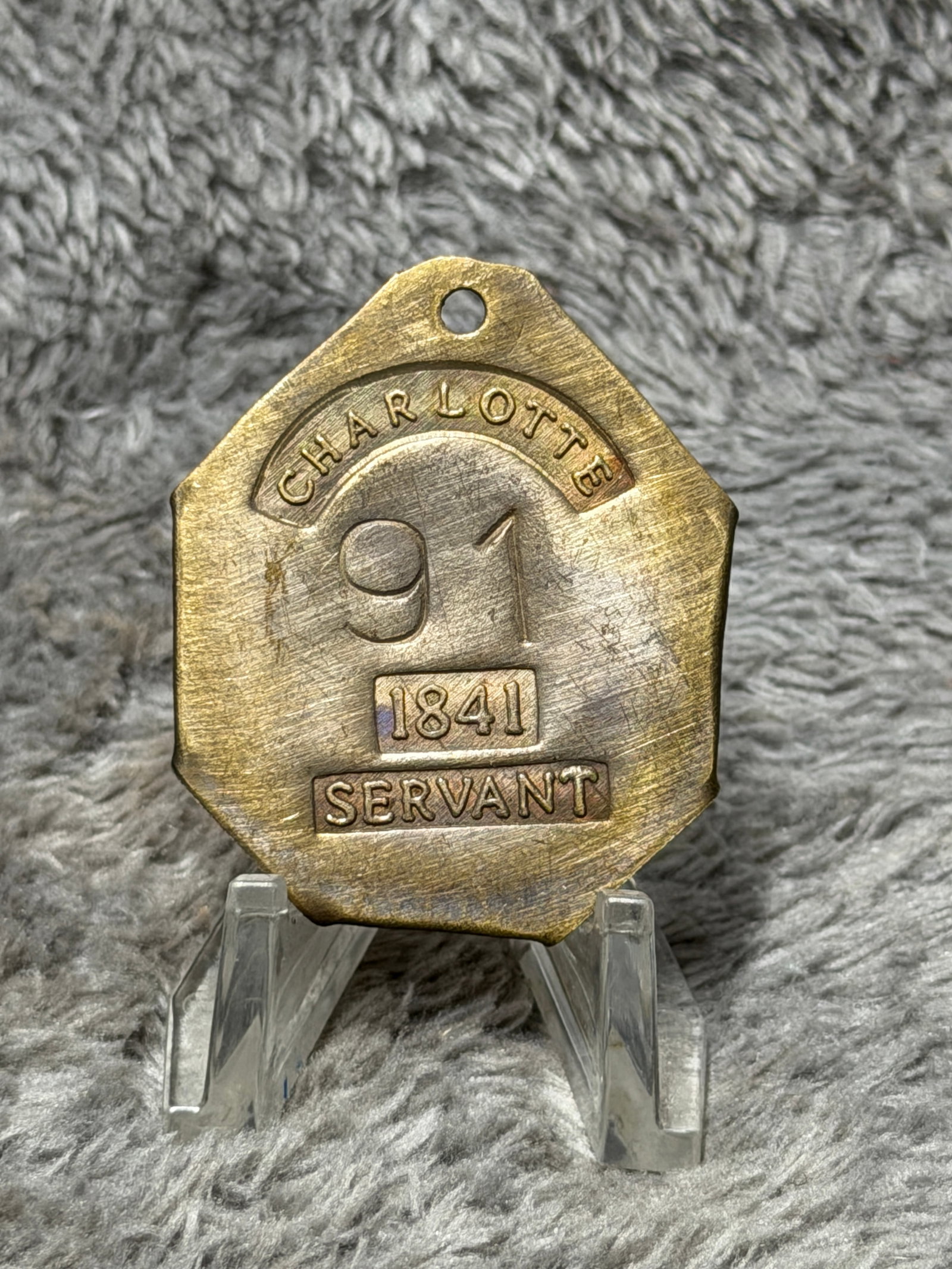 1841 Charleston, South Carolina Slave Hire Tag – Servant No. 91: Charleston, South Carolina slave hire tag dated 1841 and designated “SERVANT,” bearing the identification number 91. The multi-sided brass or copper-alloy tag features a pierced suspension hol