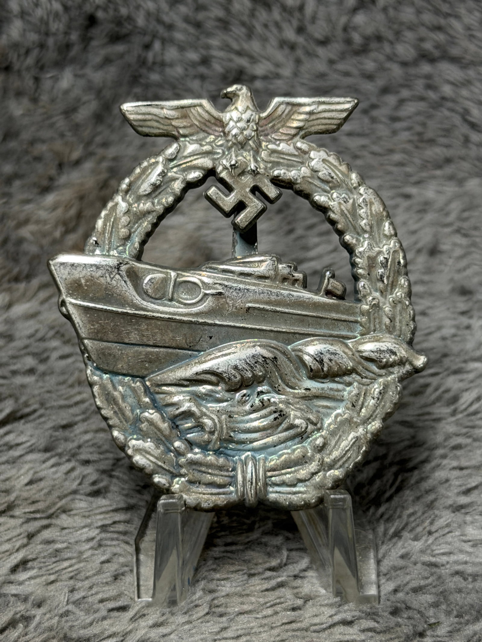 WWII German Kriegsmarine E-Boat War Badge – W.E. Peekhaus Berlin Marked: Striking WWII German Kriegsmarine E-Boat War Badge featuring a highly detailed fast attack craft cutting through raised ocean waves, surrounded by a naval wreath and surmounted by the German national 