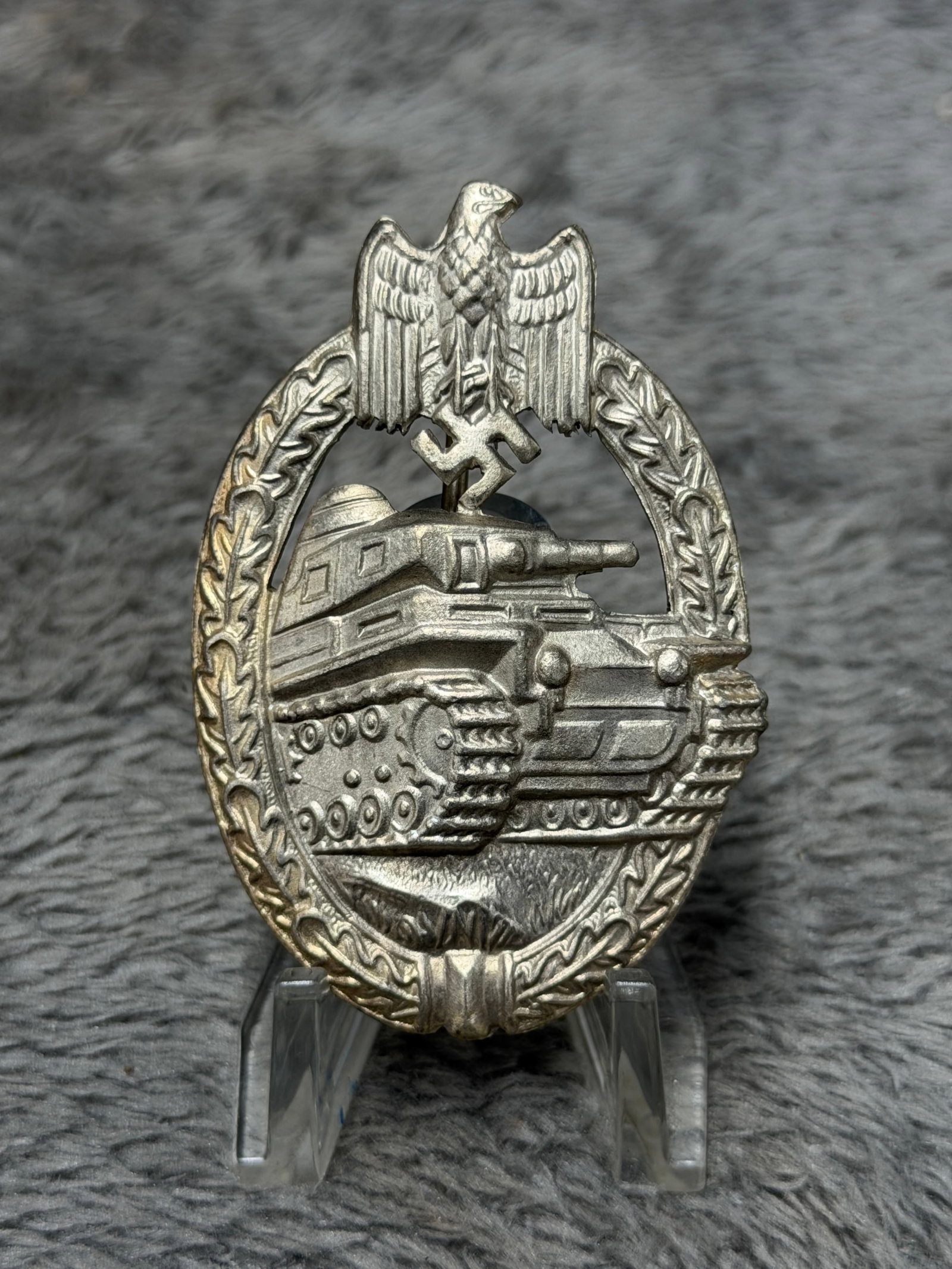 WWII German Panzer Assault Badge – Armored Combat Tank Award: WWII German Panzer Assault Badge featuring the distinctive armored fighting vehicle motif surrounded by an oval oak-leaf wreath. The central design depicts a German tank advancing across the battlefie