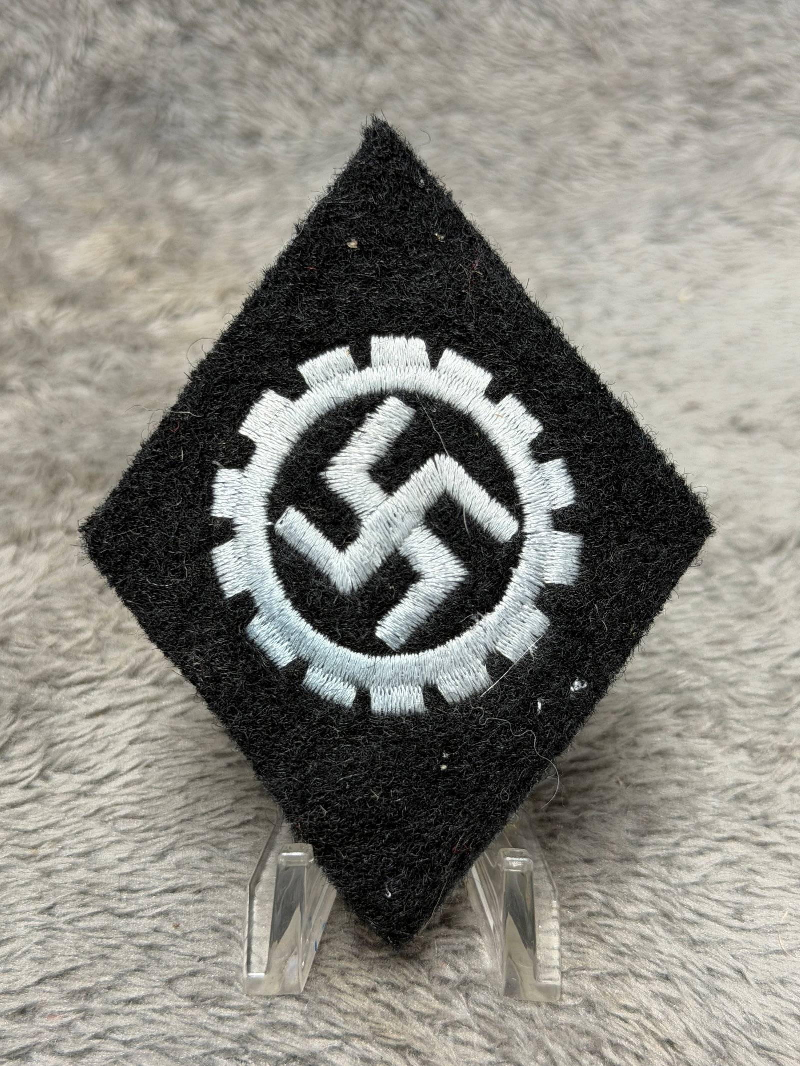 WWII German DAF Deutsche Arbeitsfront Membership Sleeve Insignia – Cogwheel & Swastika Embroidered: WWII German Deutsche Arbeitsfront (DAF), or German Labor Front, textile insignia featuring the organization’s distinctive cogwheel enclosing a central swastika. The emblem is executed in light-color