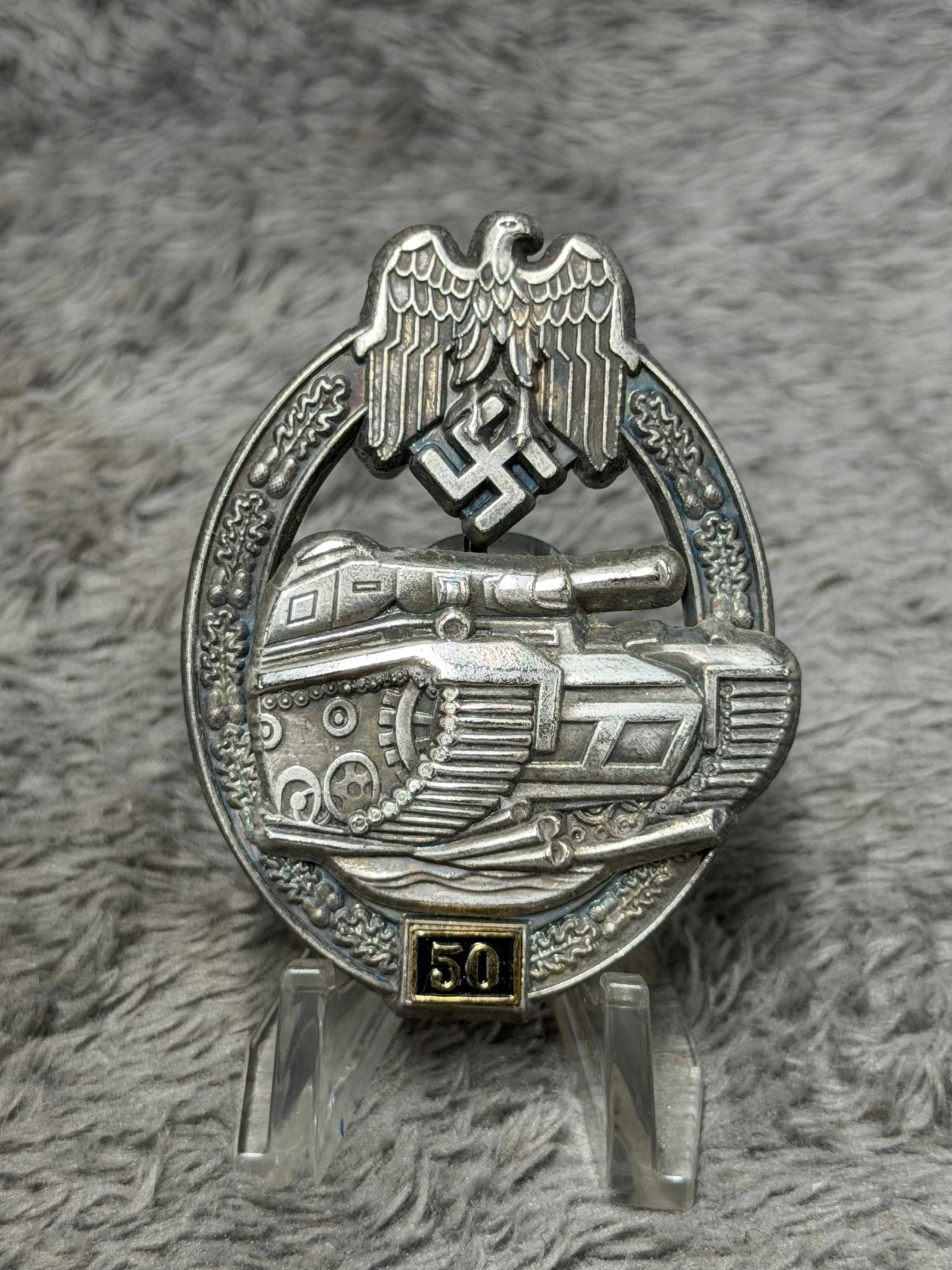 WWII German Panzer Assault Badge for 50 Engagements – JFS Marked: WWII German Panzer Assault Badge featuring the distinctive armored tank advancing across the central field beneath a Wehrmacht eagle and swastika, surrounded by an oval oak-leaf wreath. Mounted at the