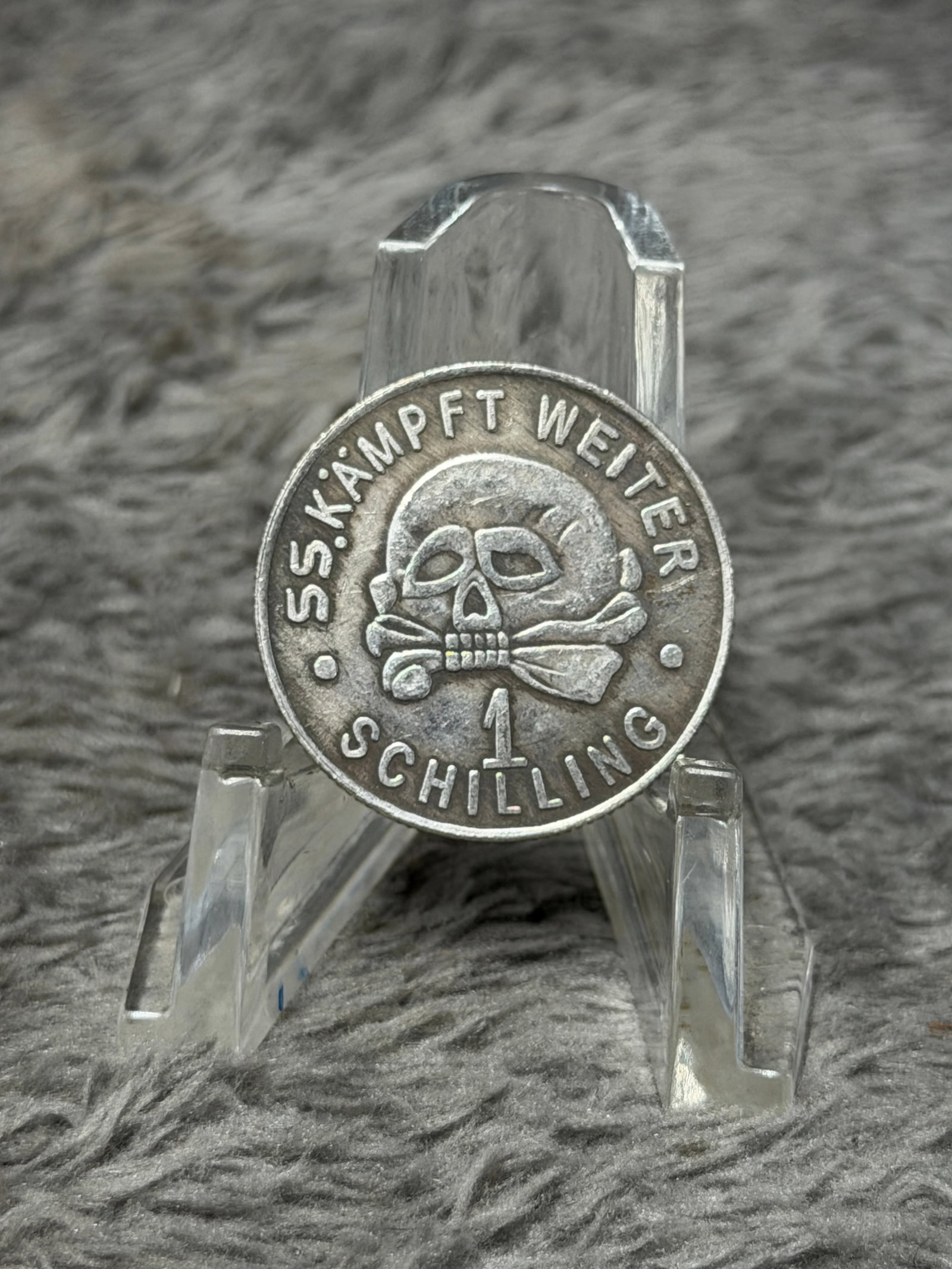 WWII German SS “Meine Ehre Heißt Treue?? Totenkopf 1 Schilling Token: WWII German SS-themed round metal token featuring prominent period imagery and inscriptions on both sides. One face displays a raised skull-and-crossbones Totenkopf motif surrounded by the wording “