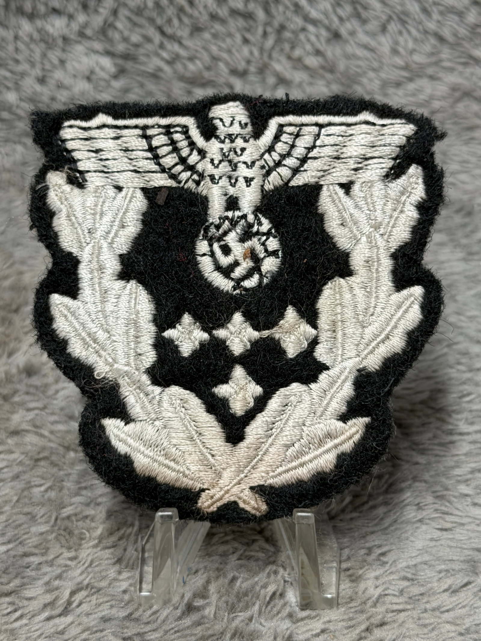 WWII German Luftwaffe General Officer Rank Sleeve Insignia – Four-Star Embroidered Eagle: WWII German Luftwaffe embroidered rank insignia featuring a prominent spread-wing Luftwaffe eagle and swastika above an elaborate arrangement of silver-white oak leaves, crossed marshal-style batons, 
