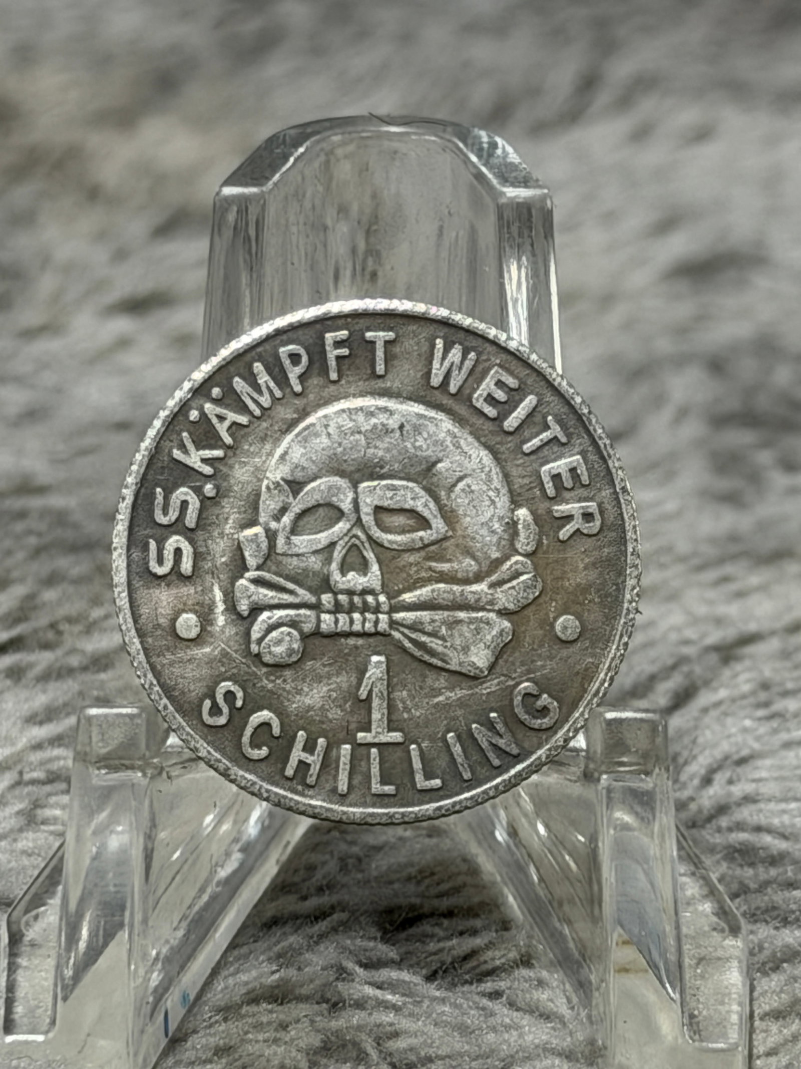 WWII German Waffen-SS “Kantinegeld?? 1939 Canteen Token – SS Totenkopf Death’s Head: WWII German Waffen-SS round metal canteen token prominently displaying a raised Totenkopf skull-and-crossbones motif with the inscription “SS-KÄMPFT WEITER” around the upper border and “1 S