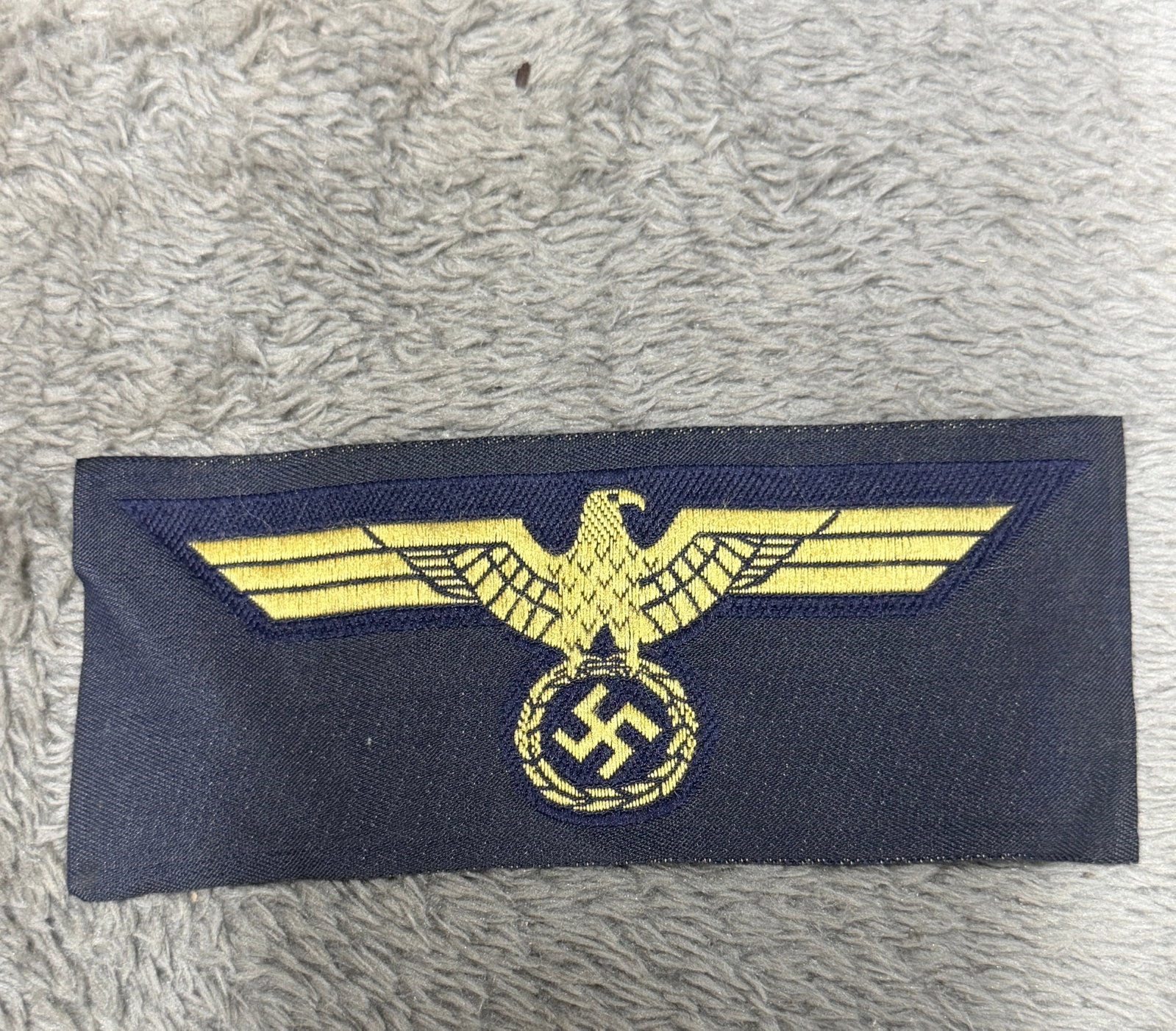 WWII German Kriegsmarine Naval Breast Eagle Insignia – Gold on Navy Blue: Striking WWII German Kriegsmarine naval uniform breast eagle featuring a finely embroidered golden-yellow national eagle with outstretched wings clutching a wreathed swastika, executed against a dark 