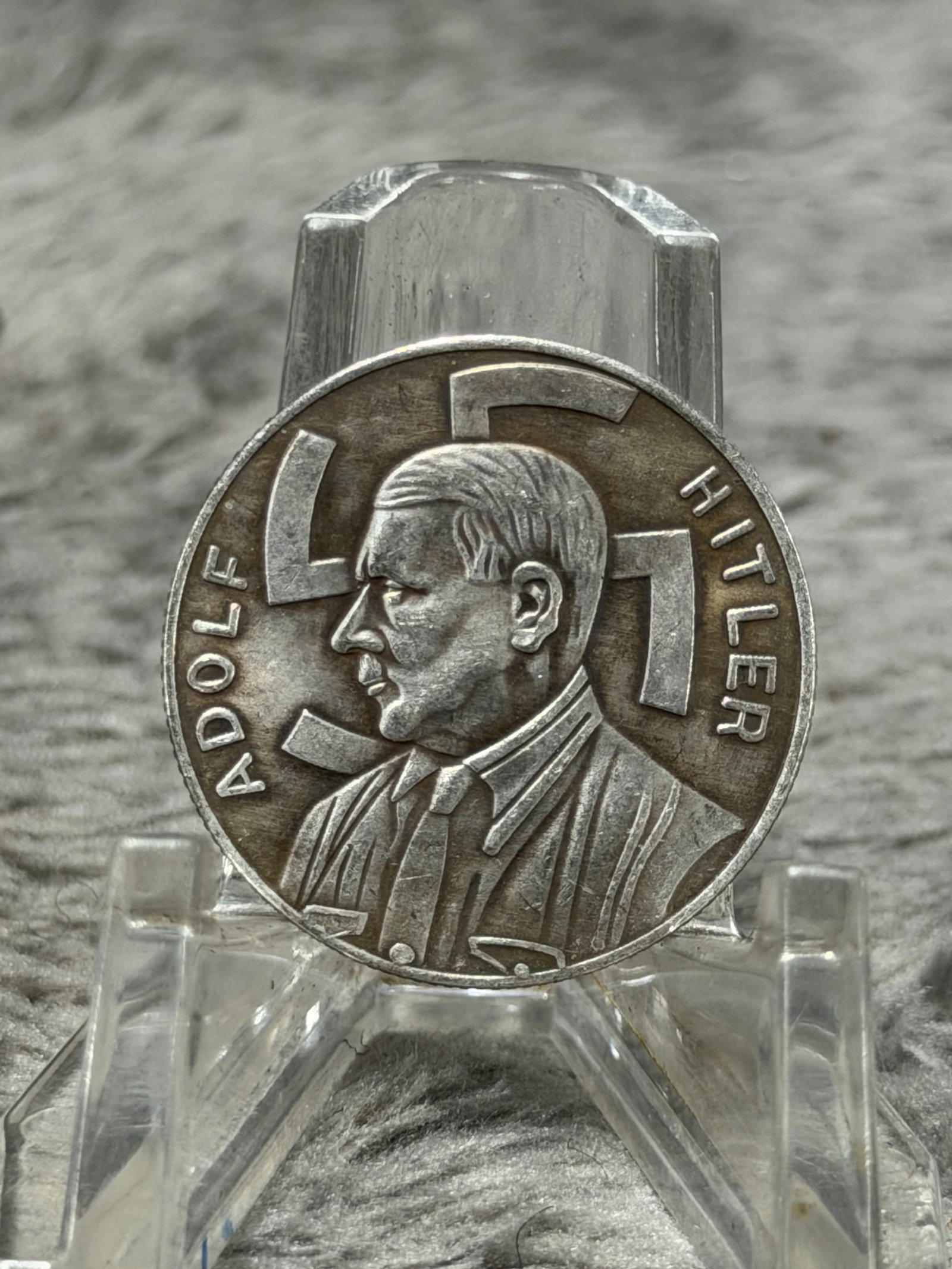 WWII German Adolf Hitler 1 Reichsmark “Gemeinnutz Geht Vor Eigennutz?? Commemorative Coin: Striking WWII-era German commemorative coin or medallion featuring a prominent left-facing portrait of Adolf Hitler set against a large swastika, with “ADOLF HITLER” arranged vertically along 