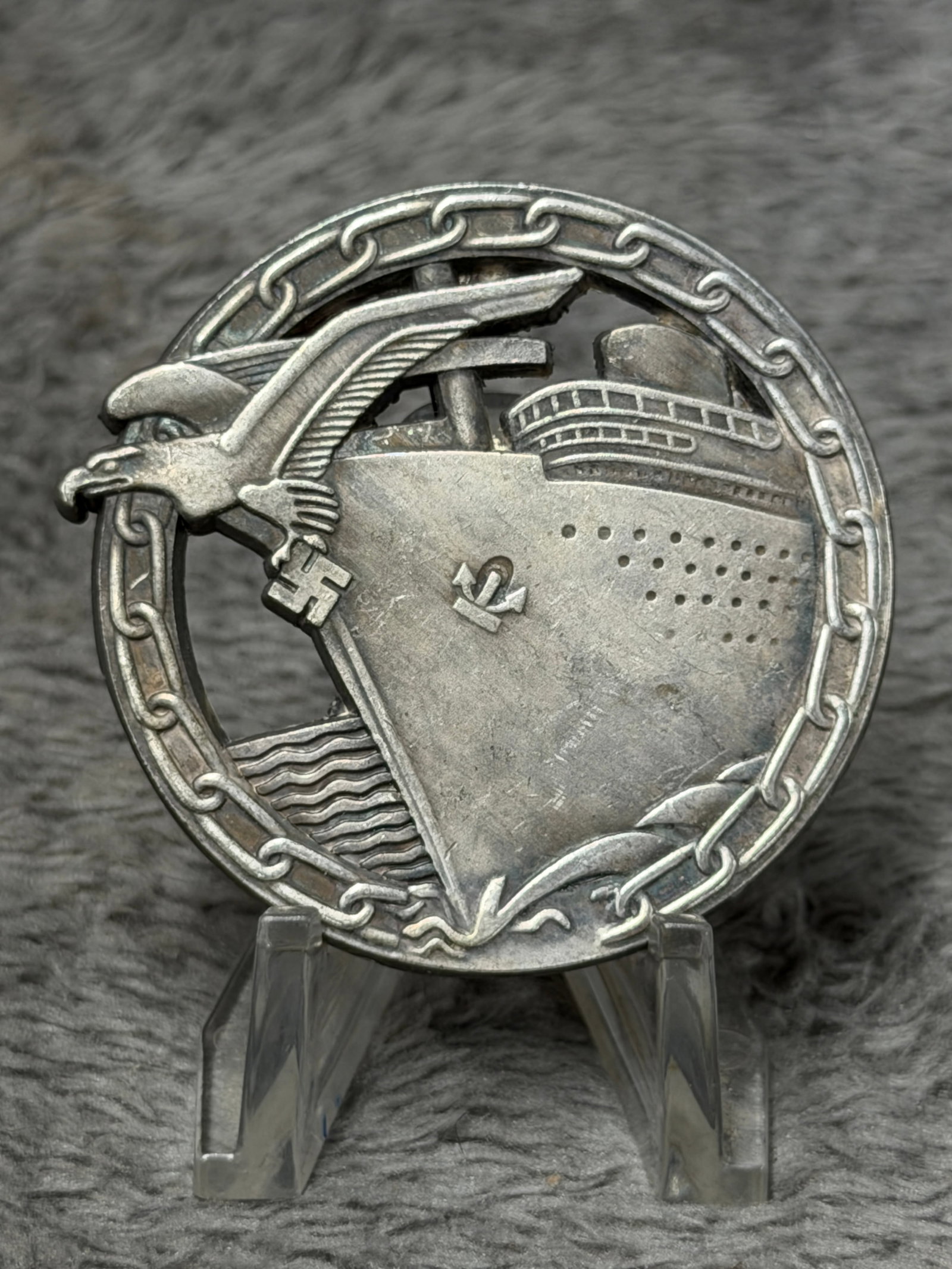 WWII German Kriegsmarine Blockade Runner Badge – Otto Placzek Berlin: Impressive WWII German Kriegsmarine Blockade Runner Badge featuring a large ocean-going merchant vessel cutting through a circular chain barrier, with a German eagle and swastika positioned prominentl