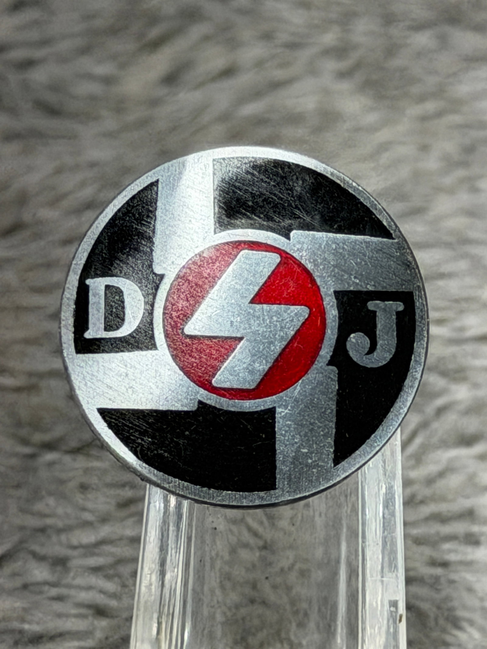 WWII German Deutsches Jungvolk DJ Membership Badge – RZM M1/129 Marked: WWII German Deutsches Jungvolk (DJ) membership badge featuring the organization’s distinctive black-and-silver geometric field with a central red circular medallion bearing the silver-toned DJ rune 