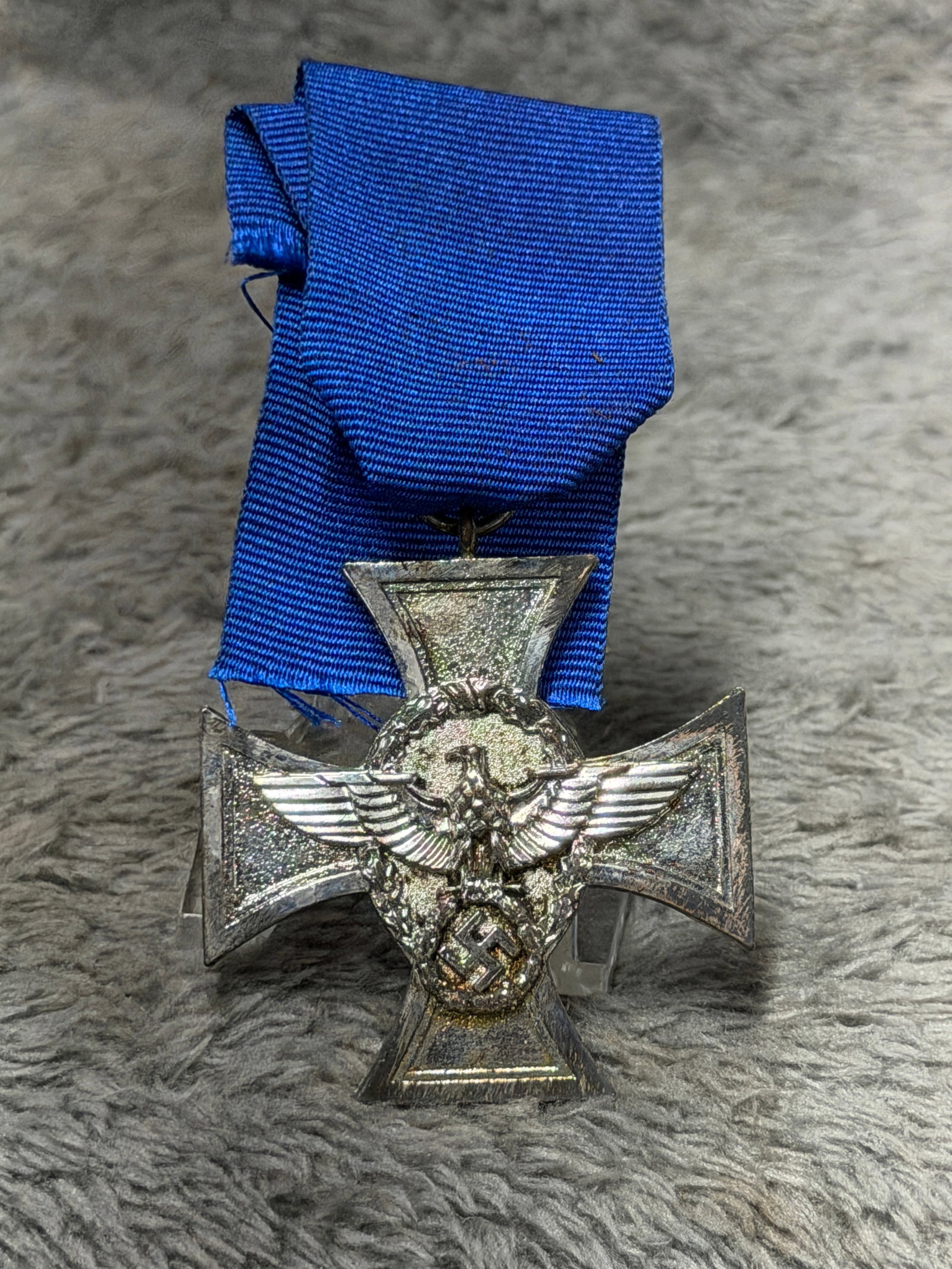 WWII German Police 25-Year Long Service Cross with Blue Ribbon: Impressive WWII German Police Long Service decoration featuring a silver-colored cross suspended from a deep blue ribbon. The obverse displays a prominent German police eagle with outstretched wings s