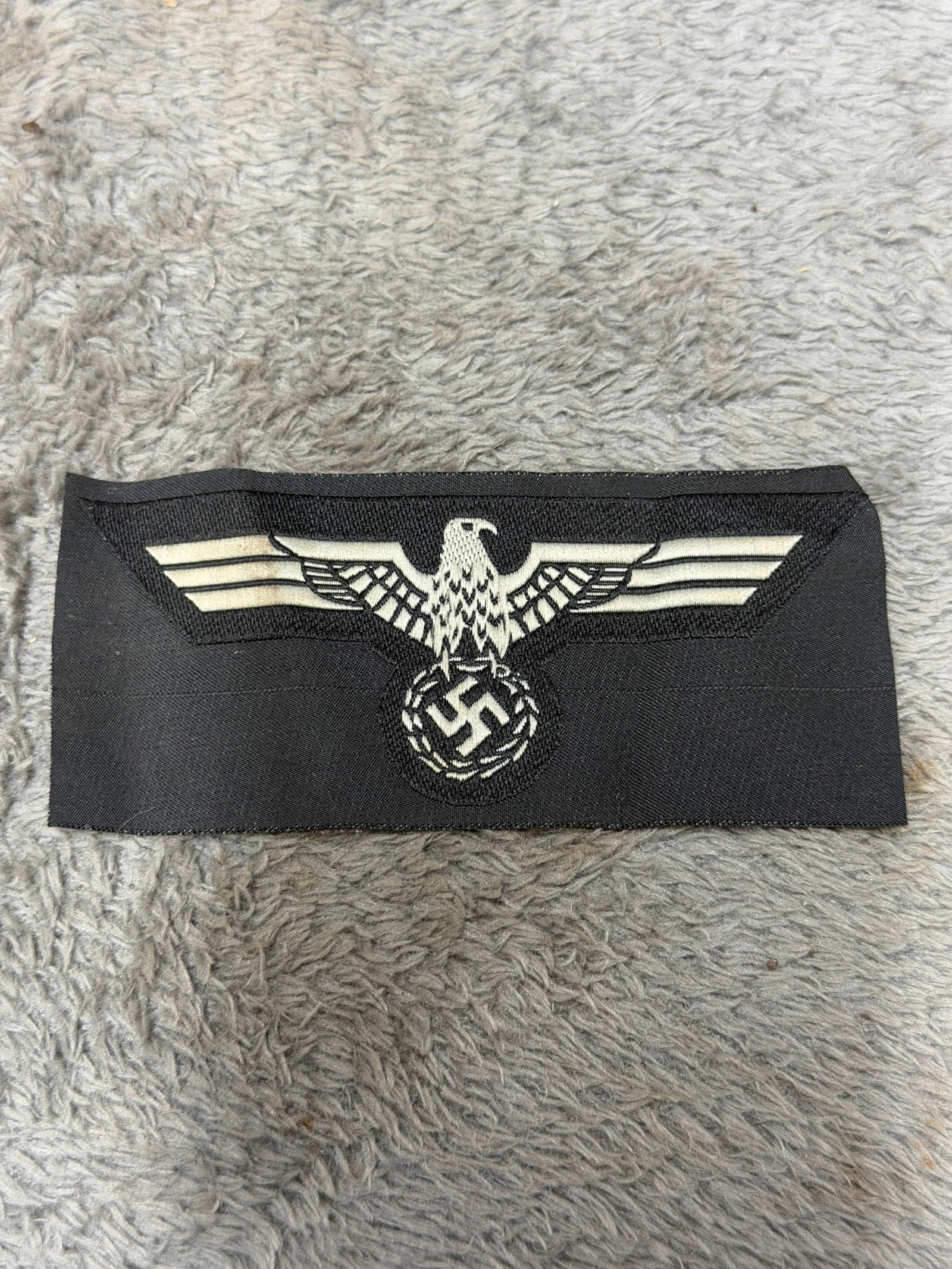 WWII German Panzer Eagle National Breast Insignia on Black Cloth: WWII German Panzer national breast eagle insignia featuring a prominently woven German eagle with fully extended wings positioned above a circular wreath enclosing a swastika. The eagle is executed in