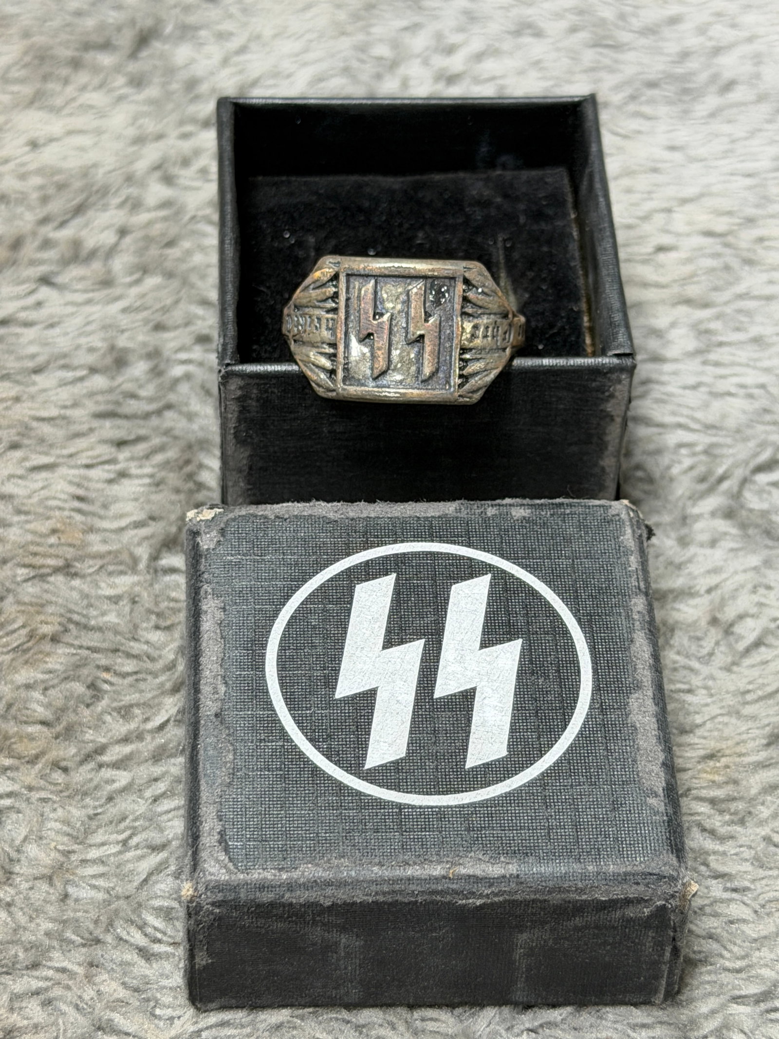 WWII German Waffen-SS SS Runes Soldier’s Ring with Presentation Box: WWII German Waffen-SS themed finger ring featuring the distinctive double SS runes prominently displayed in raised relief within a rectangular central panel. The shoulders are decorated with radiating