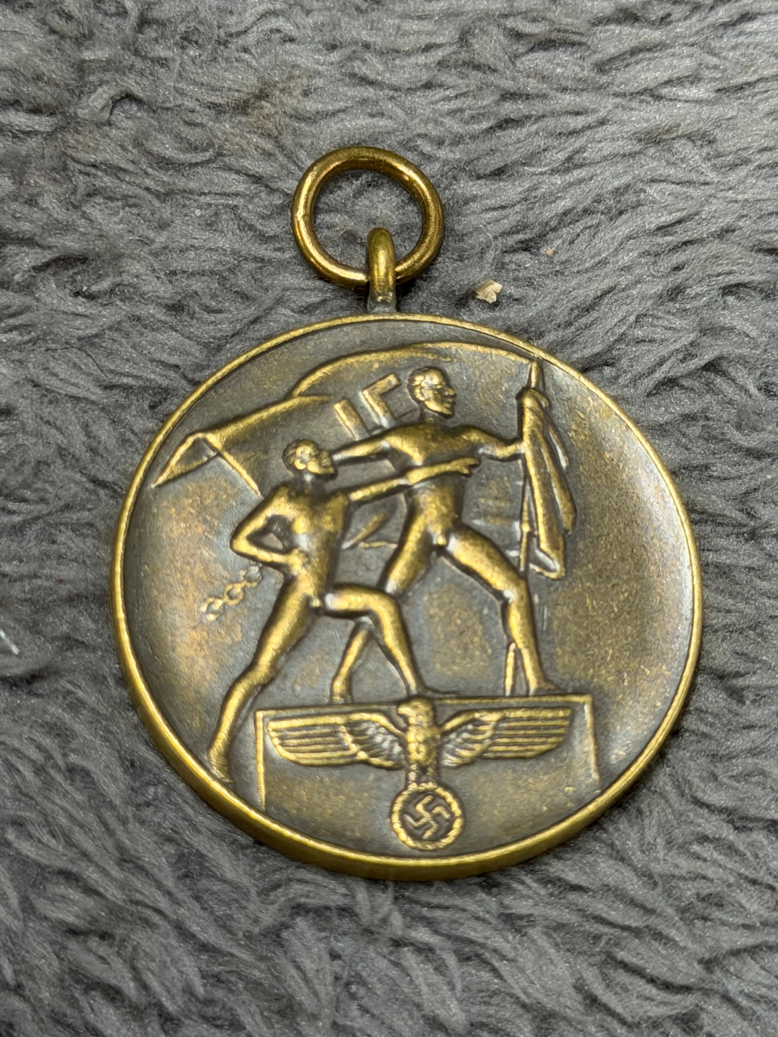 WWII German 1938 “Ein Volk, Ein Reich, Ein Führer?? 1 October Commemorative Medal: Striking WWII German commemorative medal dated 1. Oktober 1938, featuring a detailed raised scene of two figures carrying a flag above a German eagle and swastika emblem. The reverse bears the promine