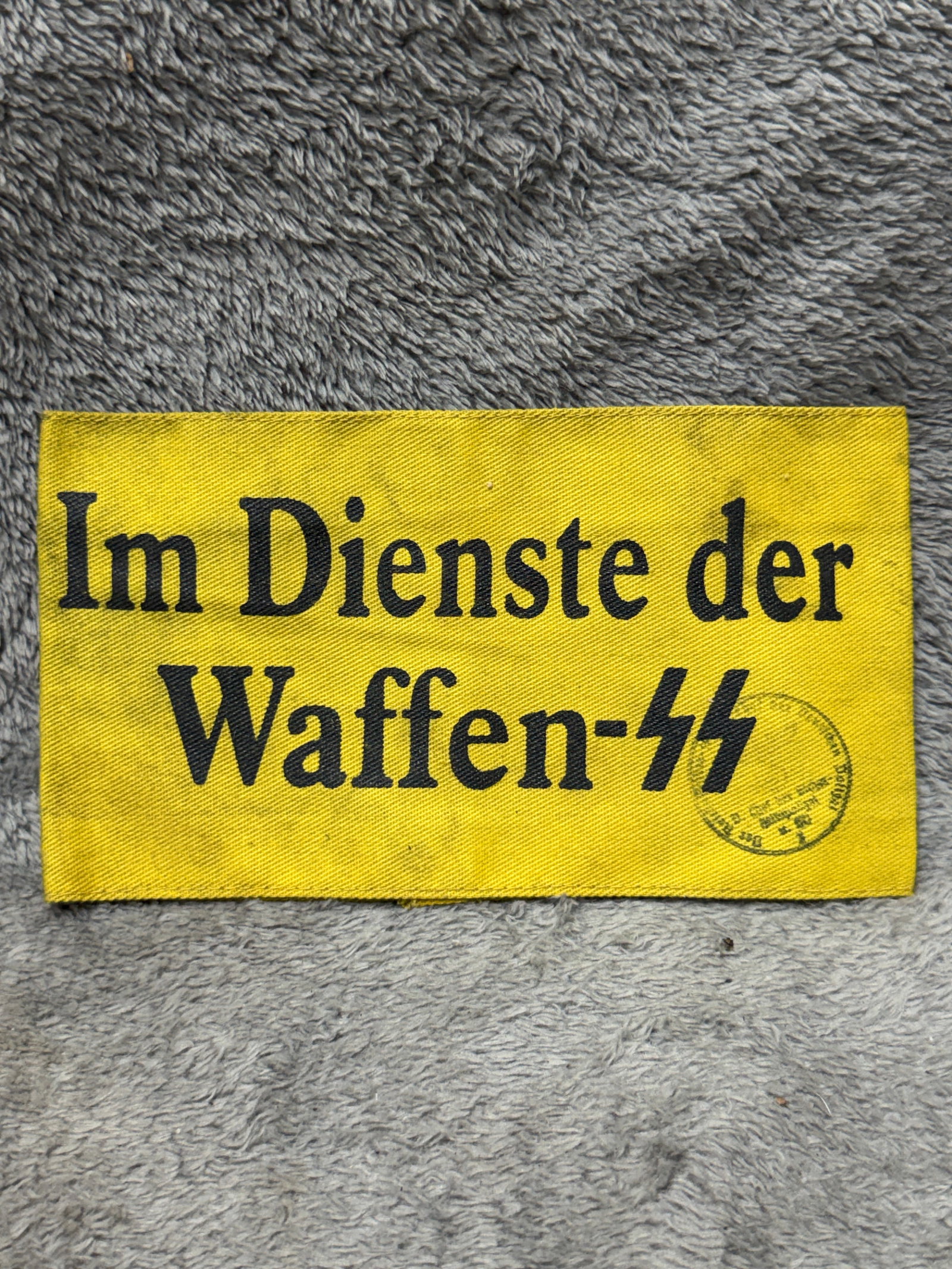 WWII German Waffen-SS “Im Dienste der Waffen-SS?? Yellow Service Armband with Ink Stamp: WWII German Waffen-SS service armband constructed of yellow cloth and prominently printed in black Gothic lettering “Im Dienste der Waffen-SS,” translating to “In the Service of the Waffen-S