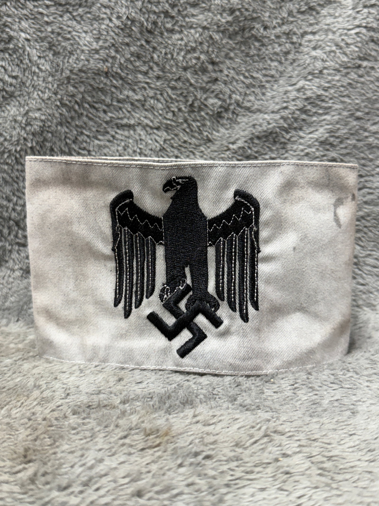 WWII German Kriegsmarine Naval Eagle & Swastika Identification Armband: WWII German Kriegsmarine naval identification armband constructed from light gray cloth and featuring a large centrally applied black embroidered German national eagle clutching a swastika. The promin