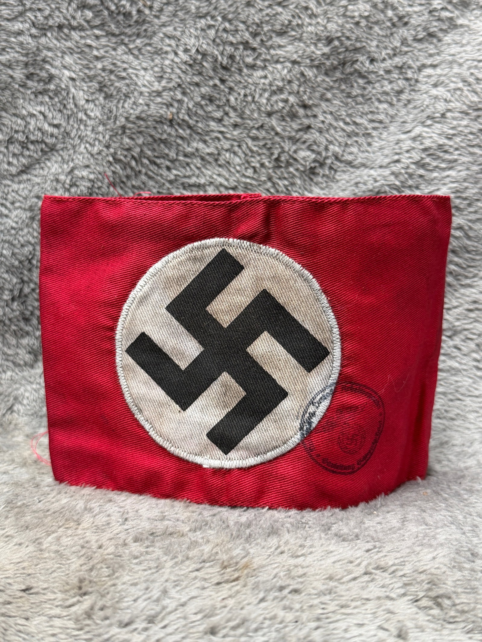 WWII German NSDAP Party Swastika Armband with Inspection Stamp: WWII German NSDAP armband constructed of red cloth with a centrally applied white circular field bearing a bold black swastika. The white roundel is separately applied to the red body and secured arou