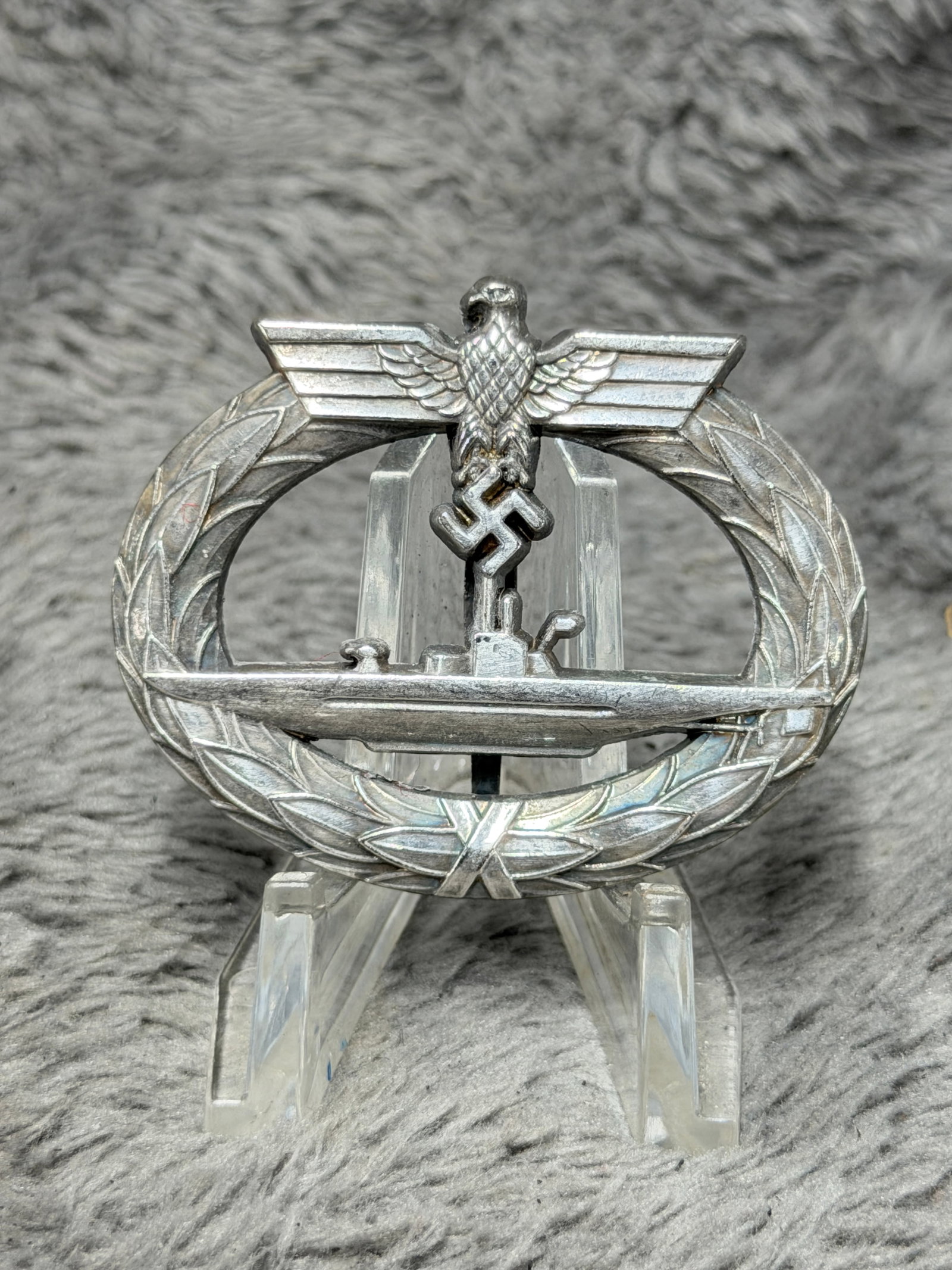 WWII German Kriegsmarine U-Boat War Badge – Schwerin Berlin 68: WWII German Kriegsmarine U-Boat War Badge featuring the distinctive oval laurel wreath surrounding a detailed submarine viewed broadside, surmounted by a spread-wing German eagle and swastika. The rev