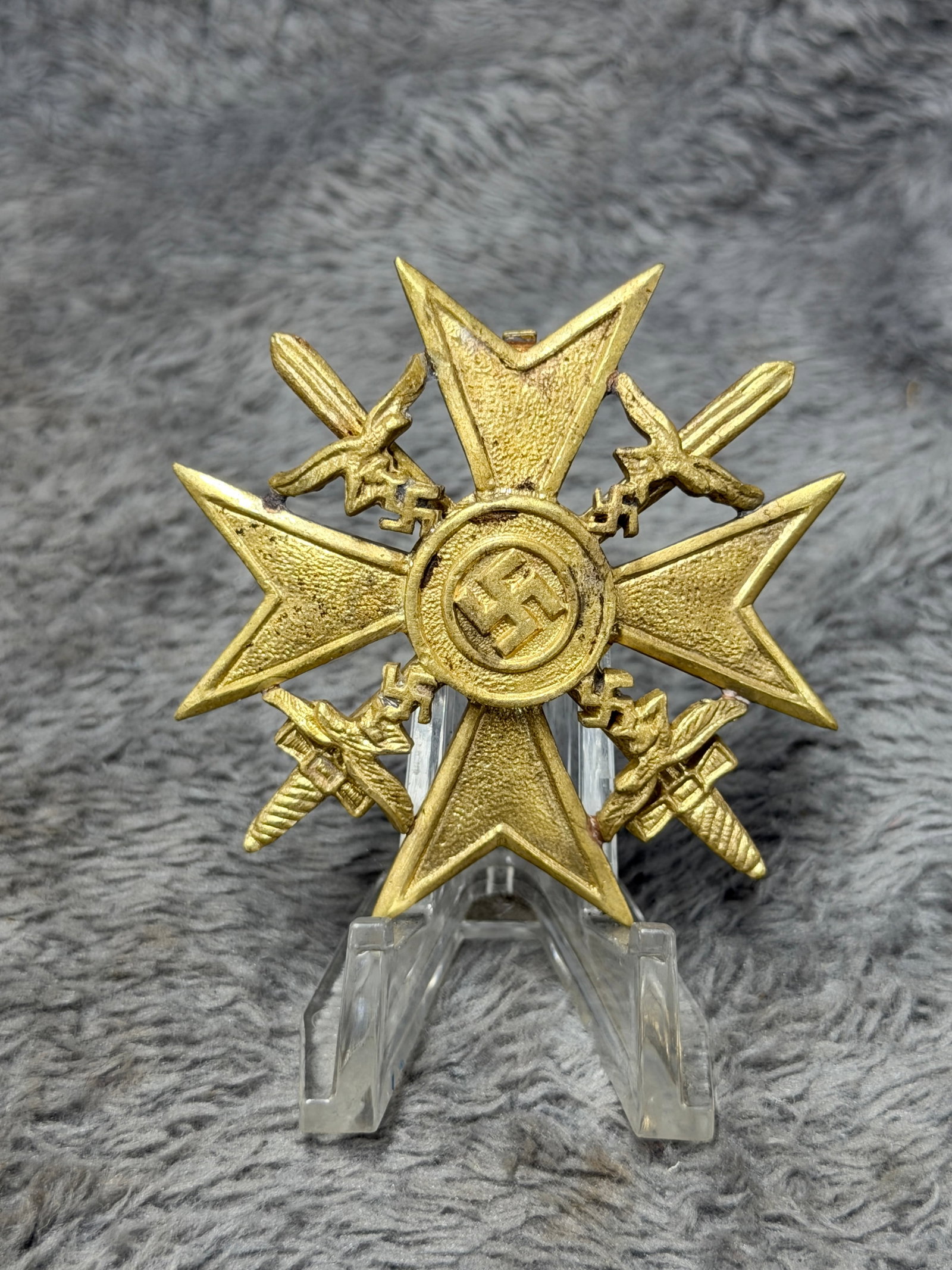 WWII German Gold Cross with Swords & Swastika Military Decoration: Striking WWII German gold-finished military decoration constructed in the form of a broad four-armed cross with sharply pointed ends and textured recessed fields. The center displays a raised swastika