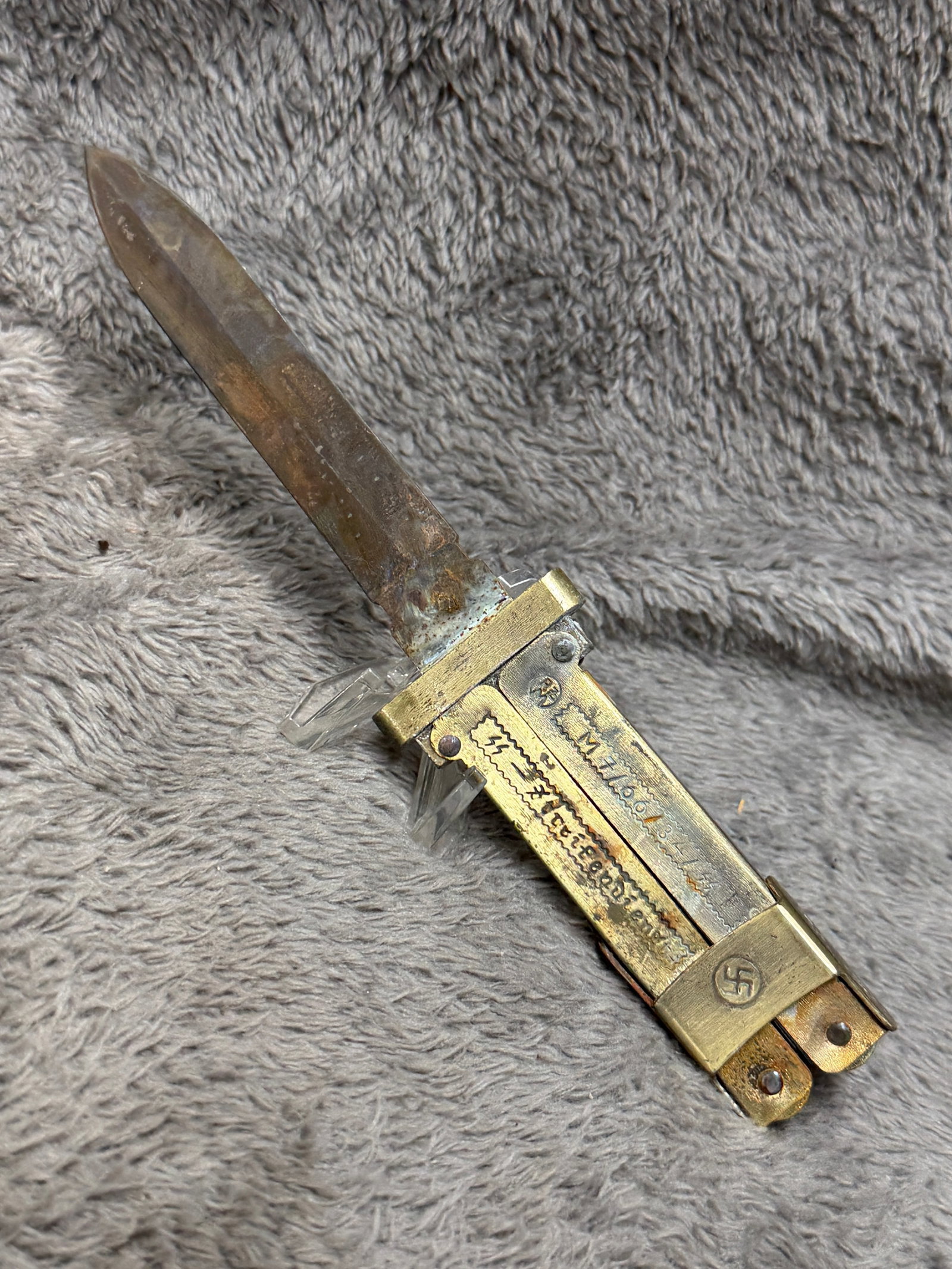WWII German Waffen-SS Paratrooper Gravity Knife with Folding Marlin Spike & Swastika Marked Body: WWII German folding utility and gravity-type knife featuring an elongated spear-point steel blade housed within a substantial brass-toned folding metal body. The multi-piece handle incorporates hinged