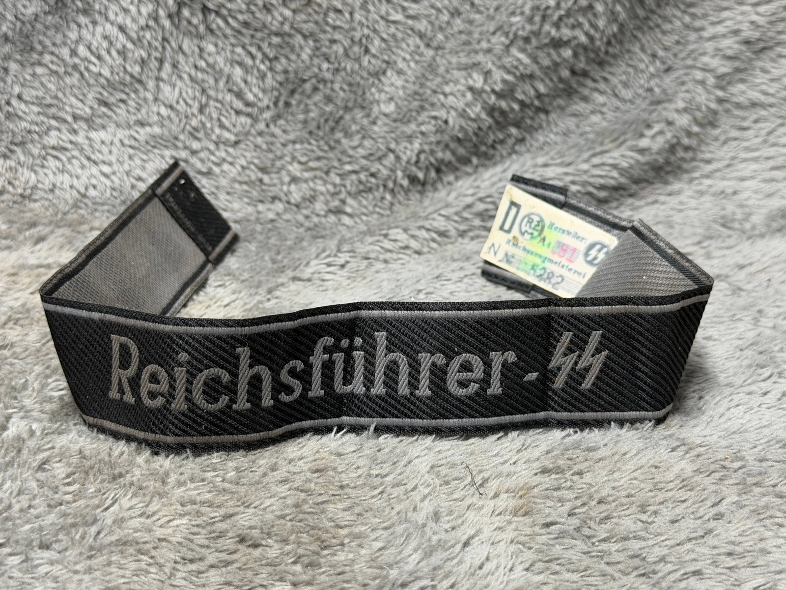 WWII German Waffen-SS “Reichsführer-SS?? Officer Cuff Title with RZM Label: WWII German Waffen-SS “Reichsführer-SS” cuff title featuring a black woven body with contrasting gray-silver embroidered “Reichsführer-SS” designation and SS runes, bordered along th