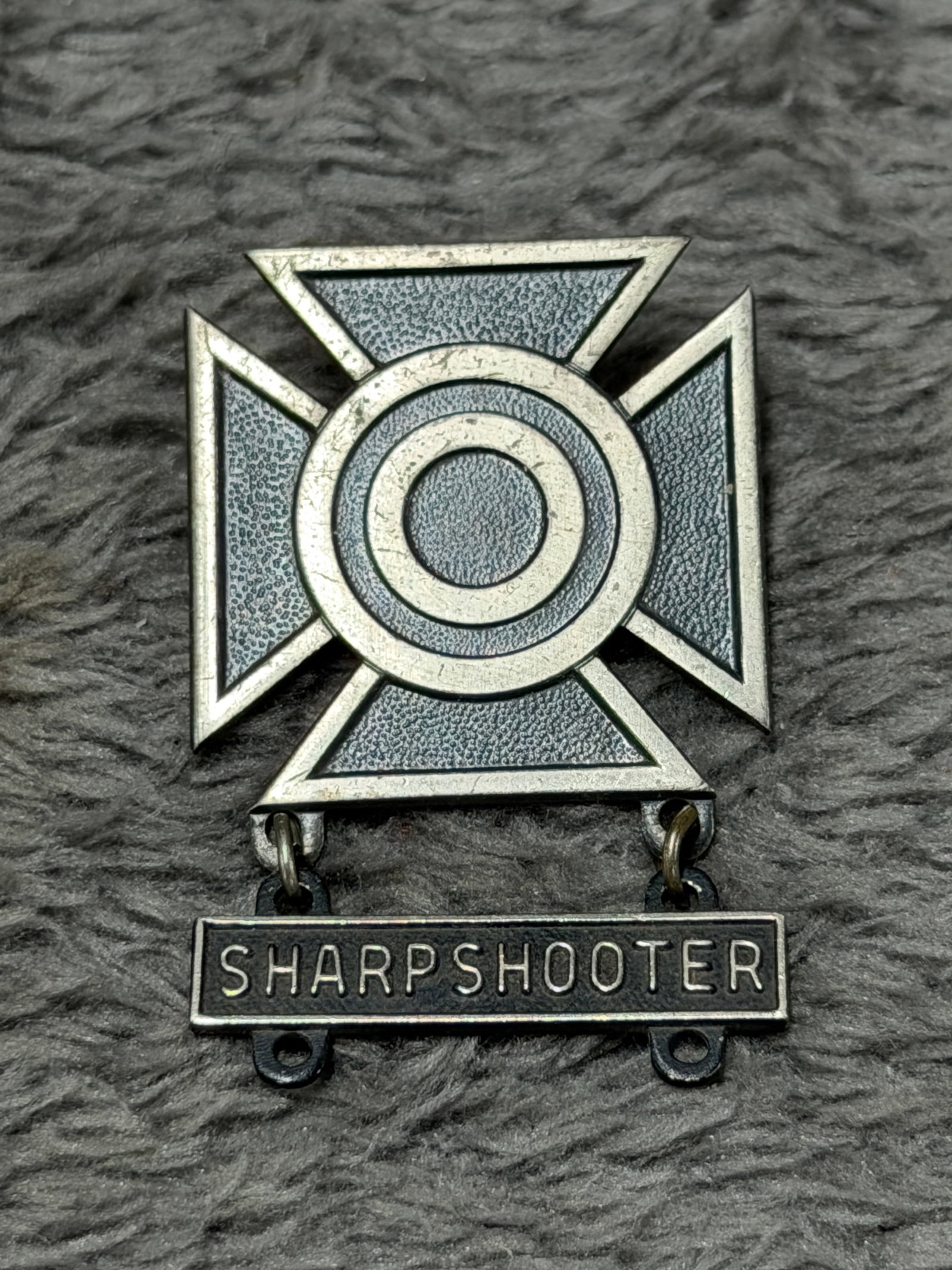 U.S. Military Sterling Sharpshooter Marksmanship Qualification Badge – Gemsco N.Y.: U.S. military marksmanship qualification badge featuring a prominent Maltese-style cross with a raised concentric bullseye target at the center and a suspended rectangular bar boldly lettered “SHARP