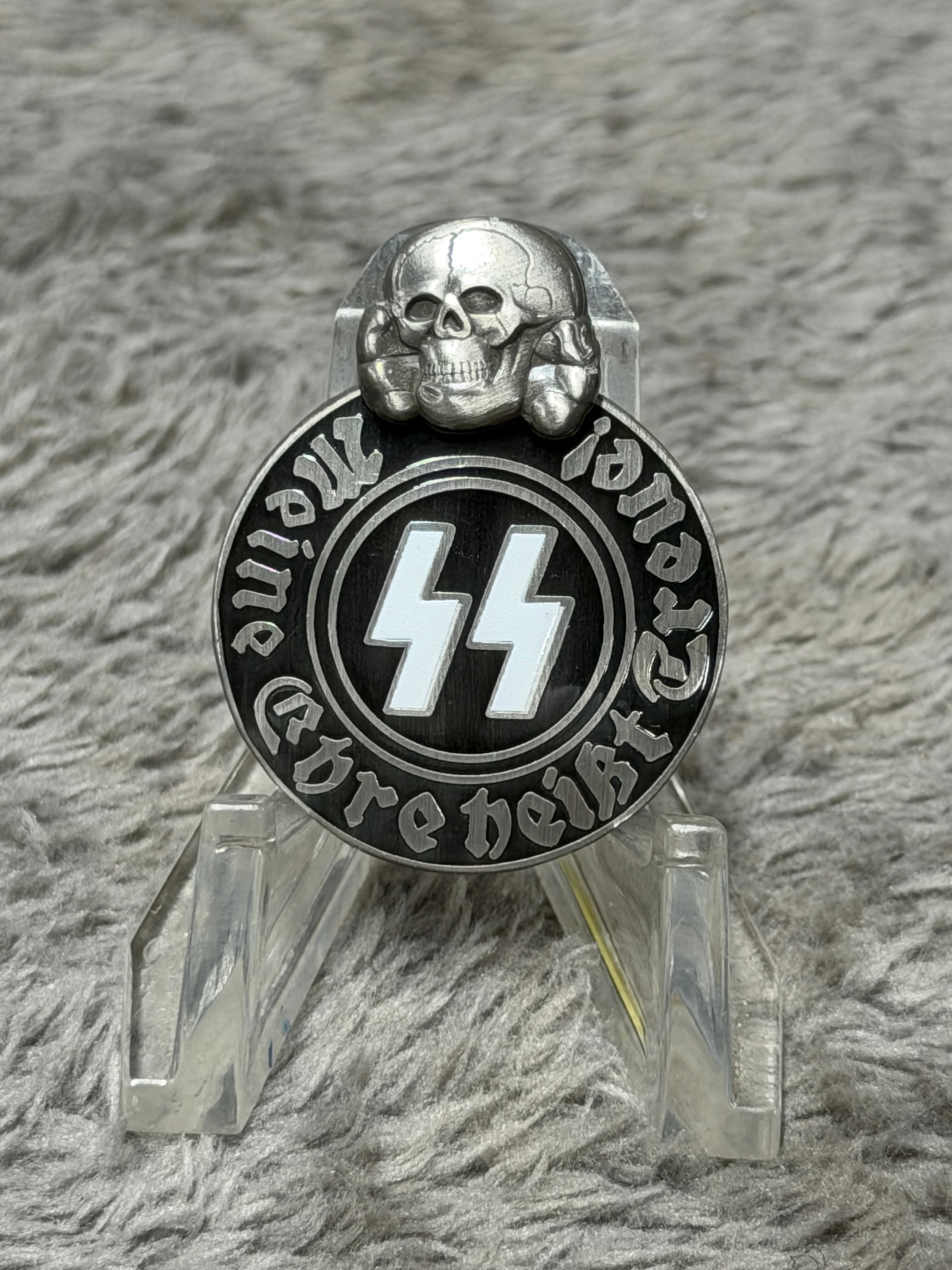 WWII German Waffen-SS “Meine Ehre Heißt Treue?? Totenkopf Enamel Membership Badge – M13/42: WWII German Waffen-SS themed enamel badge of striking oval form, surmounted by a raised Totenkopf skull-and-crossbones device and centered with prominent white SS runes against a black enameled field.