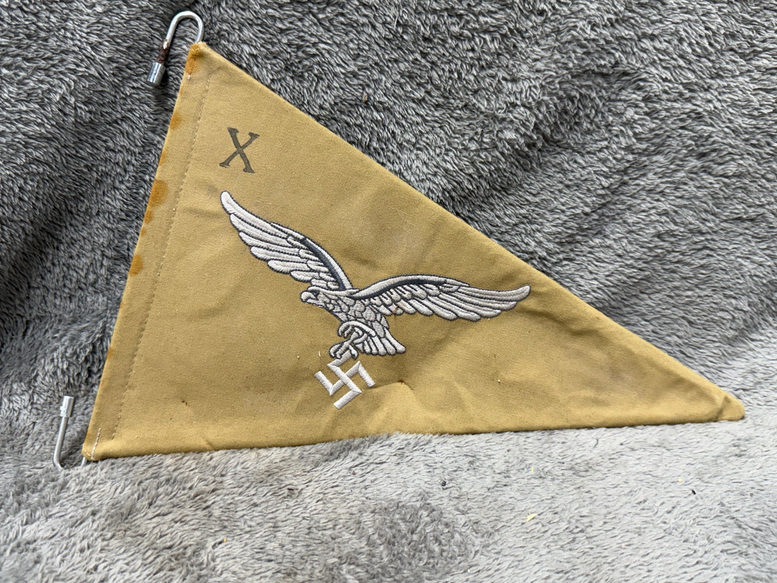 WWII German Luftwaffe Vehicle Identification Pennant with Embroidered Eagle: WWII German Luftwaffe triangular vehicle identification pennant constructed of tan to ochre-colored cloth and prominently decorated on both sides with a large embroidered Luftwaffe eagle clutching a s