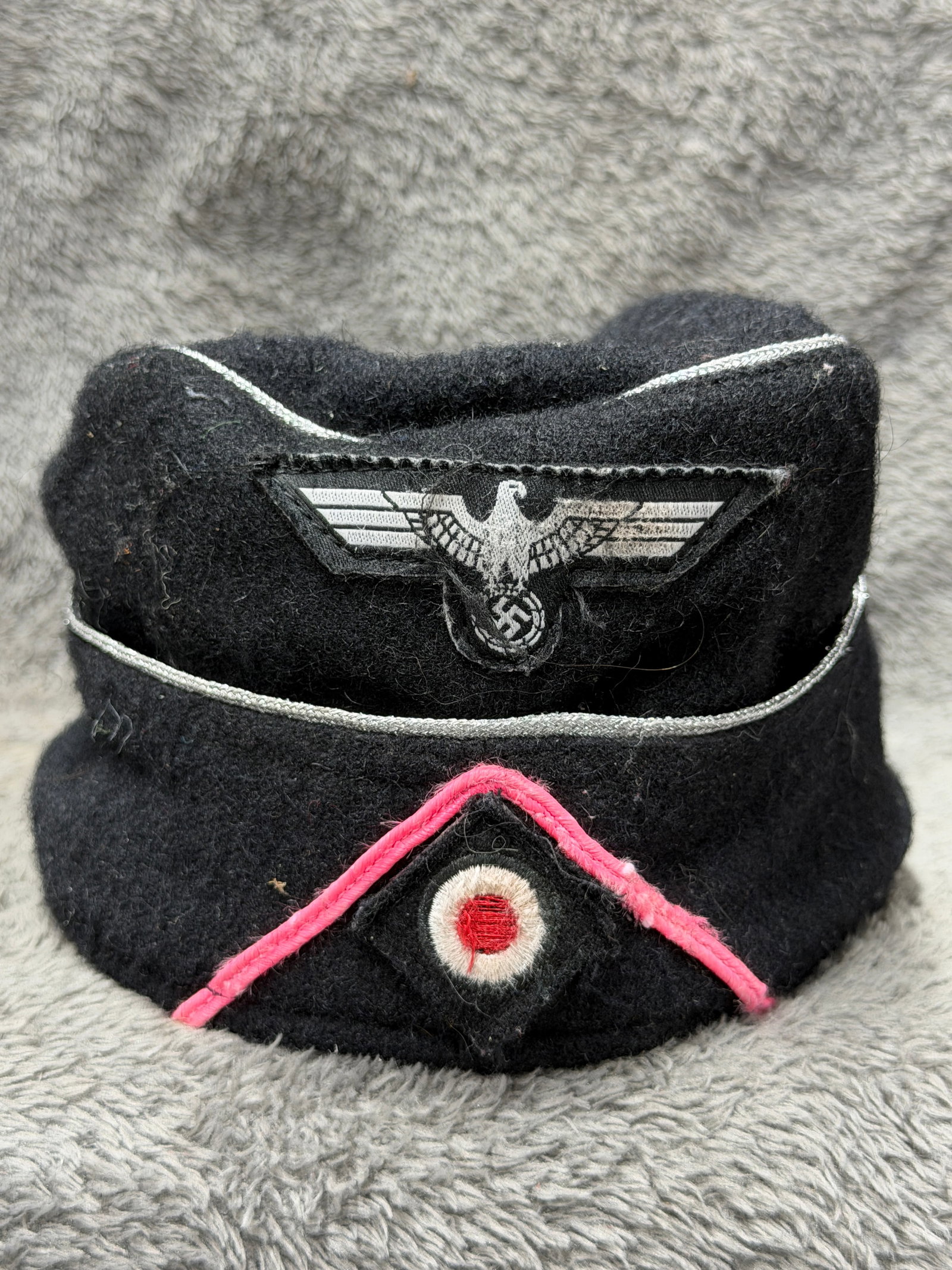 WWII German Heer Panzer Officer Black Overseas Side Cap with Pink Waffenfarbe Piping: WWII German Heer Panzer officer’s black wool overseas side cap featuring the distinctive coloration and insignia associated with Germany’s armored troops. The cap is constructed in black wool with