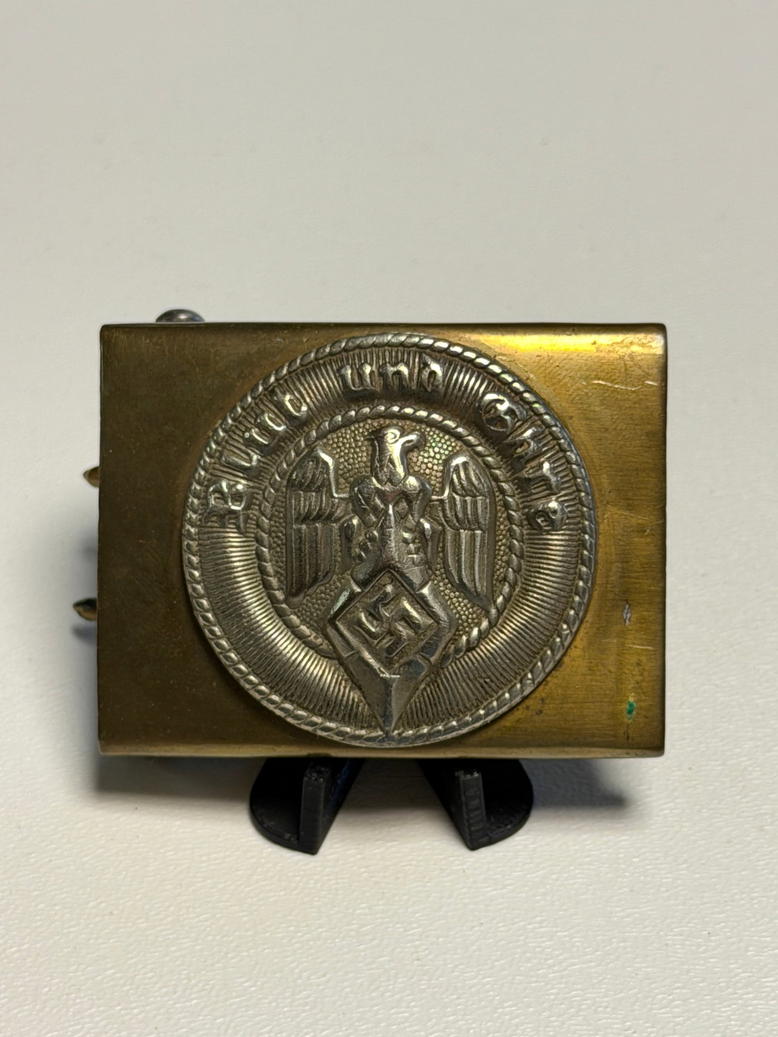 WWII German Hitler Youth “Blut und Ehre?? HJ Brass Belt Buckle: WWII German Hitler Youth (Hitlerjugend/HJ) belt buckle featuring a rectangular brass-toned body fitted with a prominent circular silver-colored central medallion. The medallion displays the Hitler You