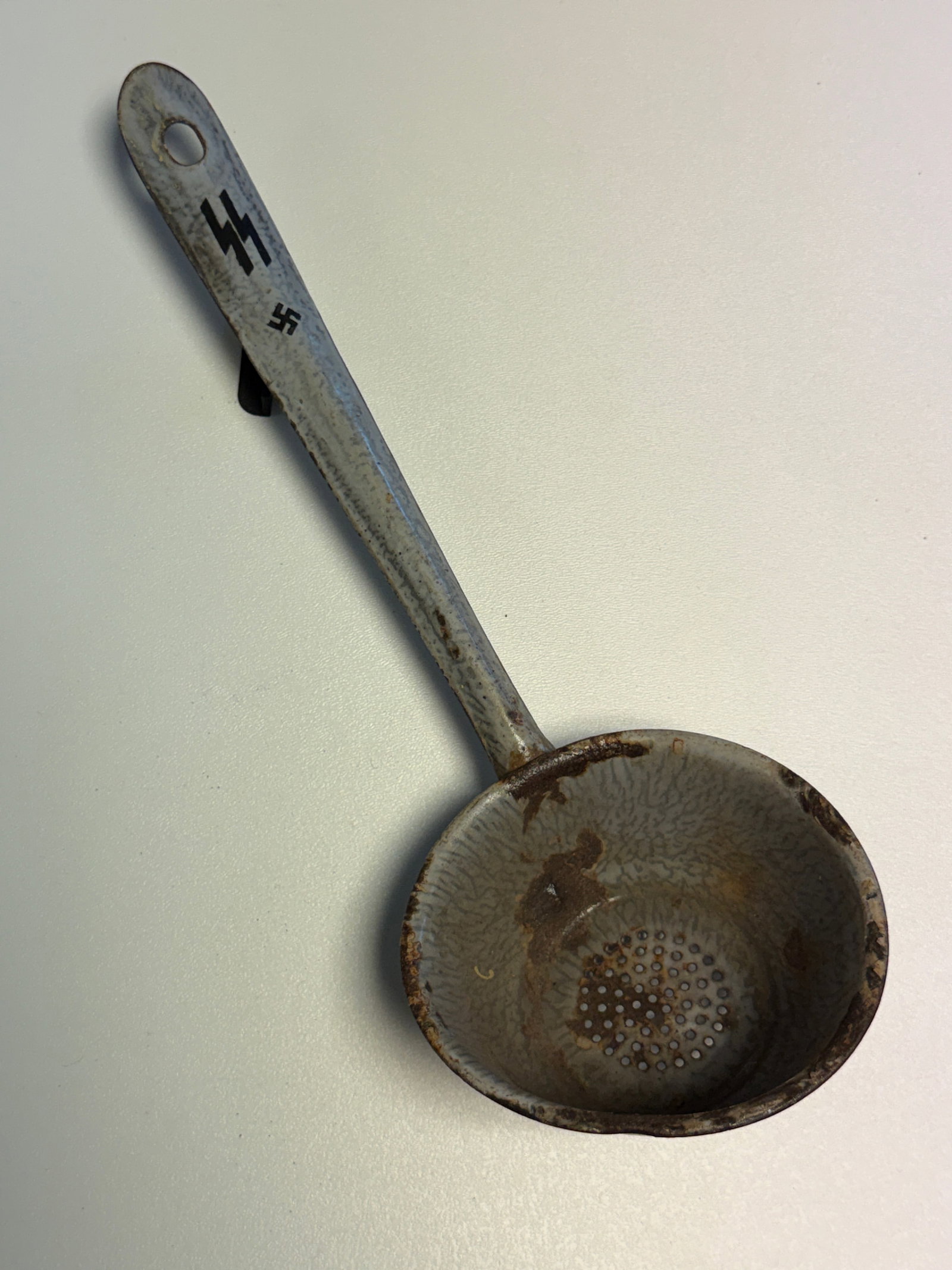 WWII German Waffen-SS Field Mess Hall Strainer Ladle with SS Runes & Swastika: WWII German military field-kitchen strainer ladle constructed of metal with a long reinforced handle and deep rounded perforated bowl intended for straining or serving food from large cooking vessels.