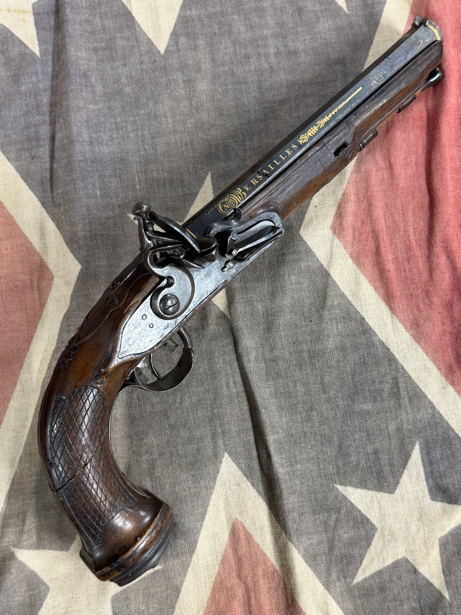 Revolutionary War Flintlock Officer’s Pistol – Gold Inlaid “Versailles" & “Boutet": Impressive Revolutionary War-period flintlock officer’s pistol featuring an elegant full wooden stock, curved checkered grip, iron furniture, flintlock firing mechanism, and an octagonal barrel rich
