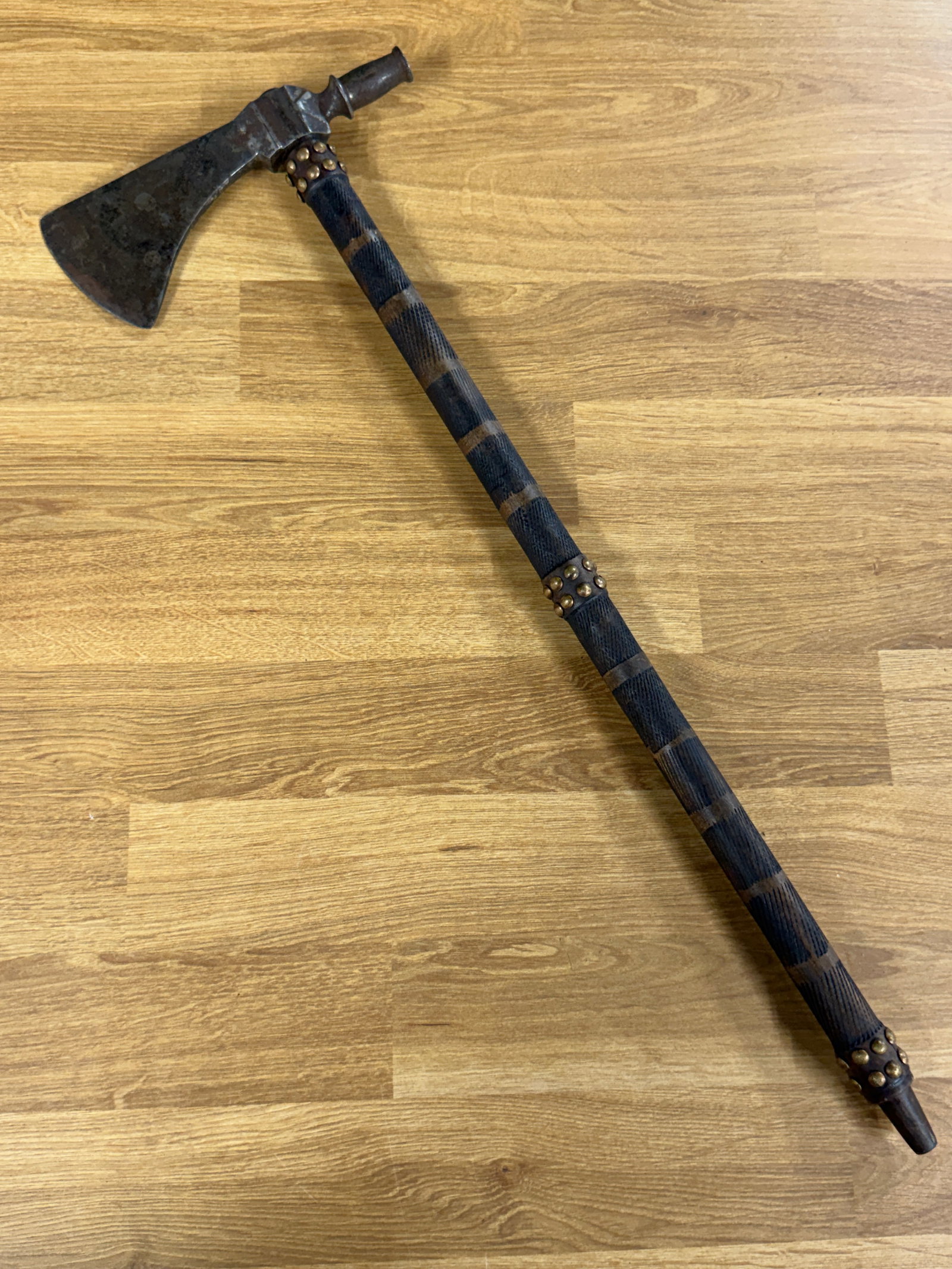 1800s Native American Plains Indian Long-Stem Pipe Tomahawk with Brass Tacks & Carved Haft: A striking 19th-century Native American Plains Indian pipe tomahawk featuring a long decorated wooden haft fitted with a substantial iron head combining a broad cutting blade with an opposing tobacco 