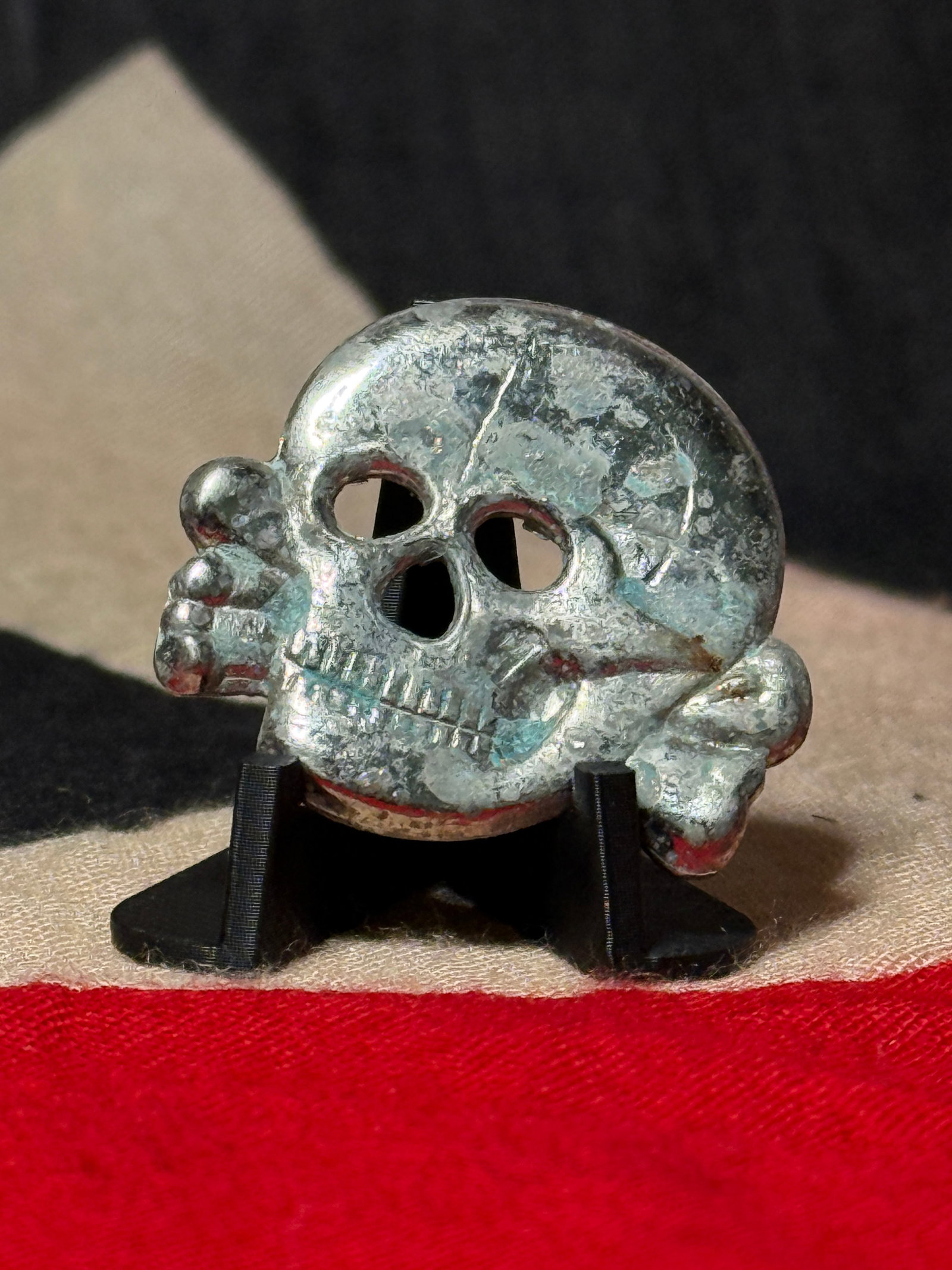 WWII German SS Totenkopf Skull & Crossbones Metal Cap Insignia: A striking WWII German SS Totenkopf skull-and-crossbones metal insignia, featuring the unmistakable death’s-head motif closely associated with SS headgear and formations during the Third Reich perio