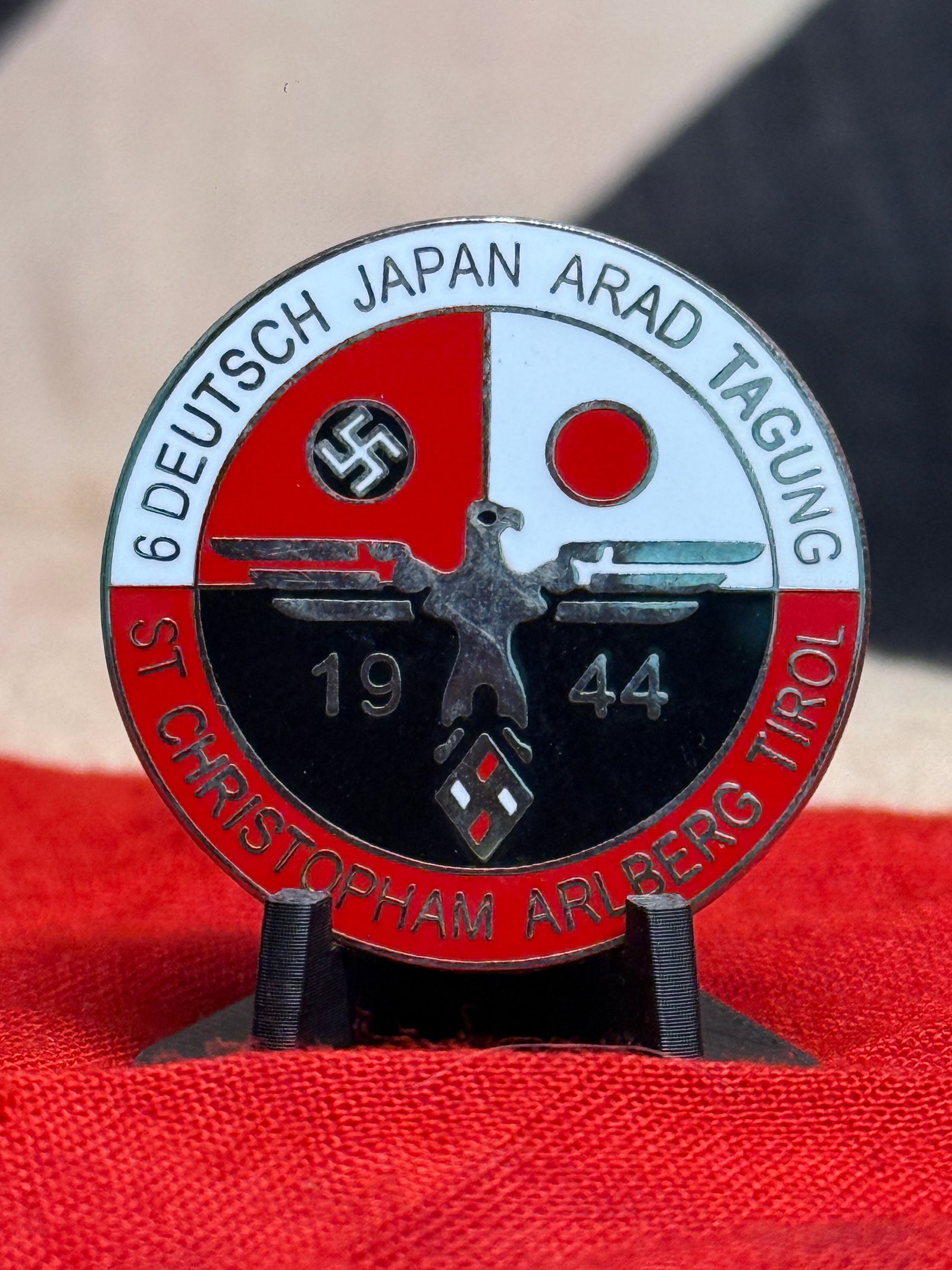 WWII German-Japanese 1944 St. Christoph am Arlberg Commemorative Badge By Hoffstattor/BONN Ges.: A striking circular enamel badge inscribed “6 DEUTSCH JAPAN ARAD TAGUNG” across the upper border and “ST CHRISTOPHAM ARLBERG TIROL” around the lower portion, with the date 1944 divided