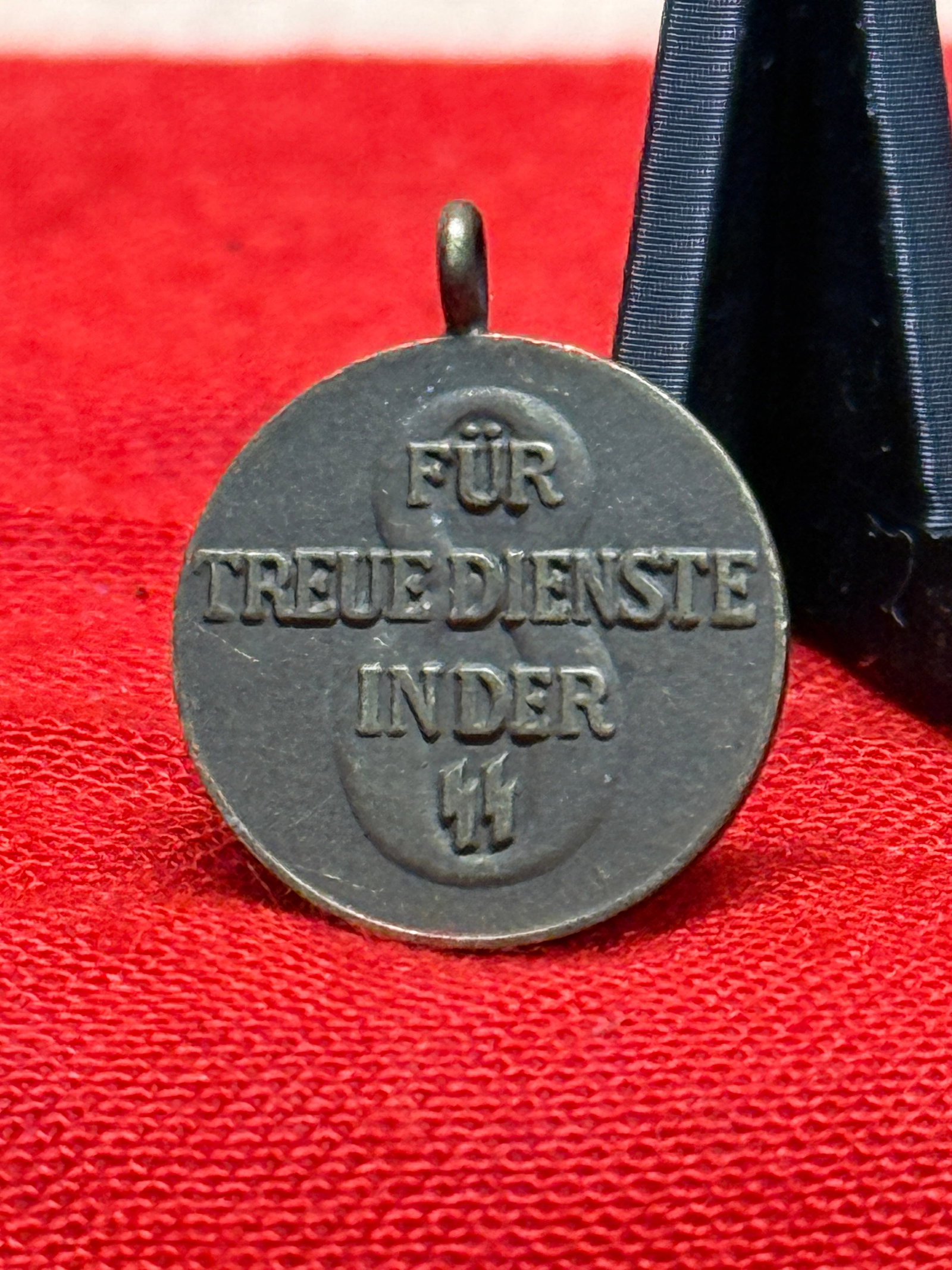 WWII German SS 8-Year Long Service Medal – “Für Treue Dienste in der SS: A circular WWII German SS long-service medal awarded for eight years of service, featuring a deeply relief-rendered design on both sides. One face displays a large swastika with SS runes positioned wi